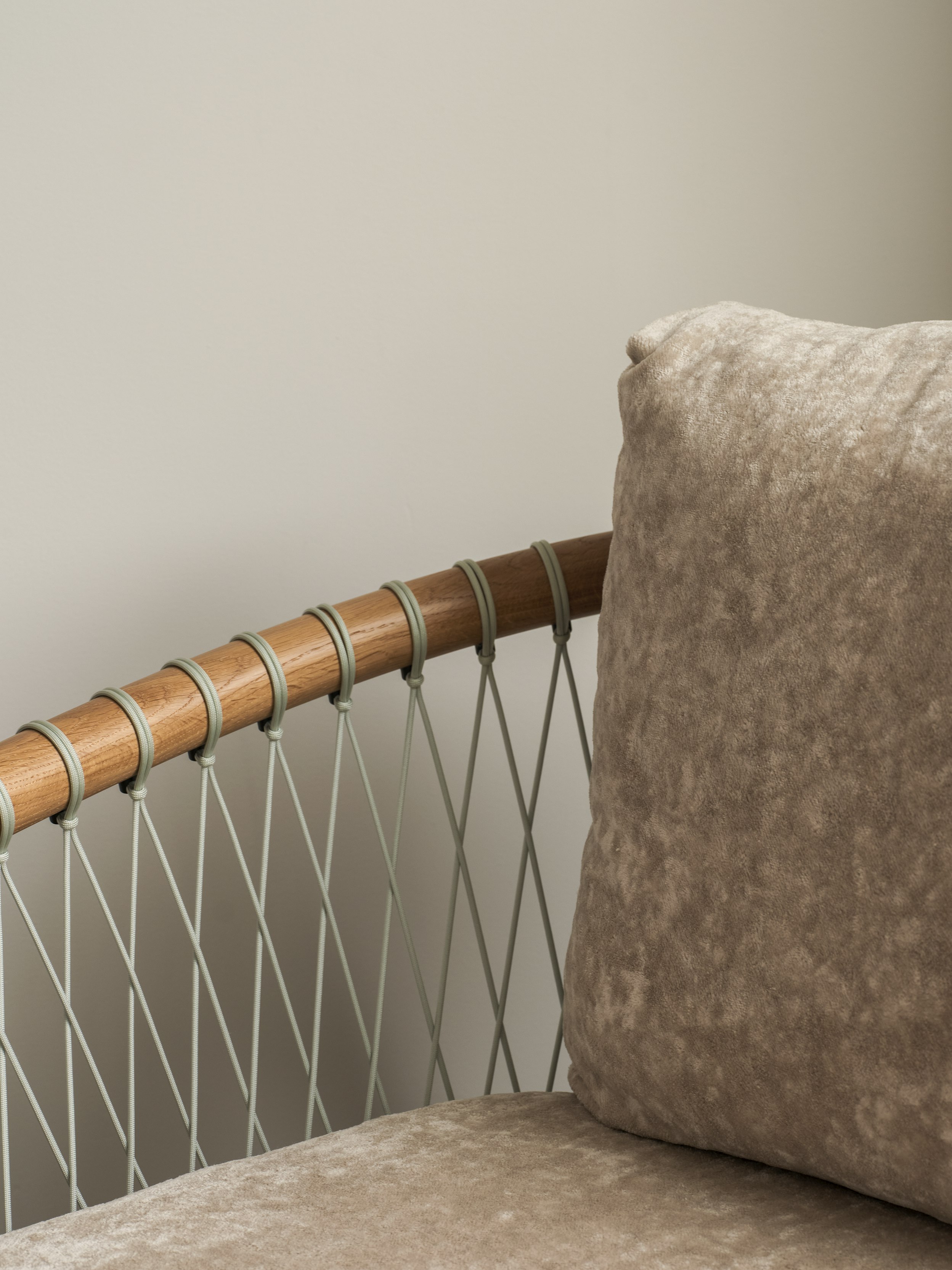 Detail view of a Crosshatch Chair arm, back, and seat, with a Natural Oak frame and grey parachute cords, upholstered with Linen Velvet in Obelisk, viewed at an angle.