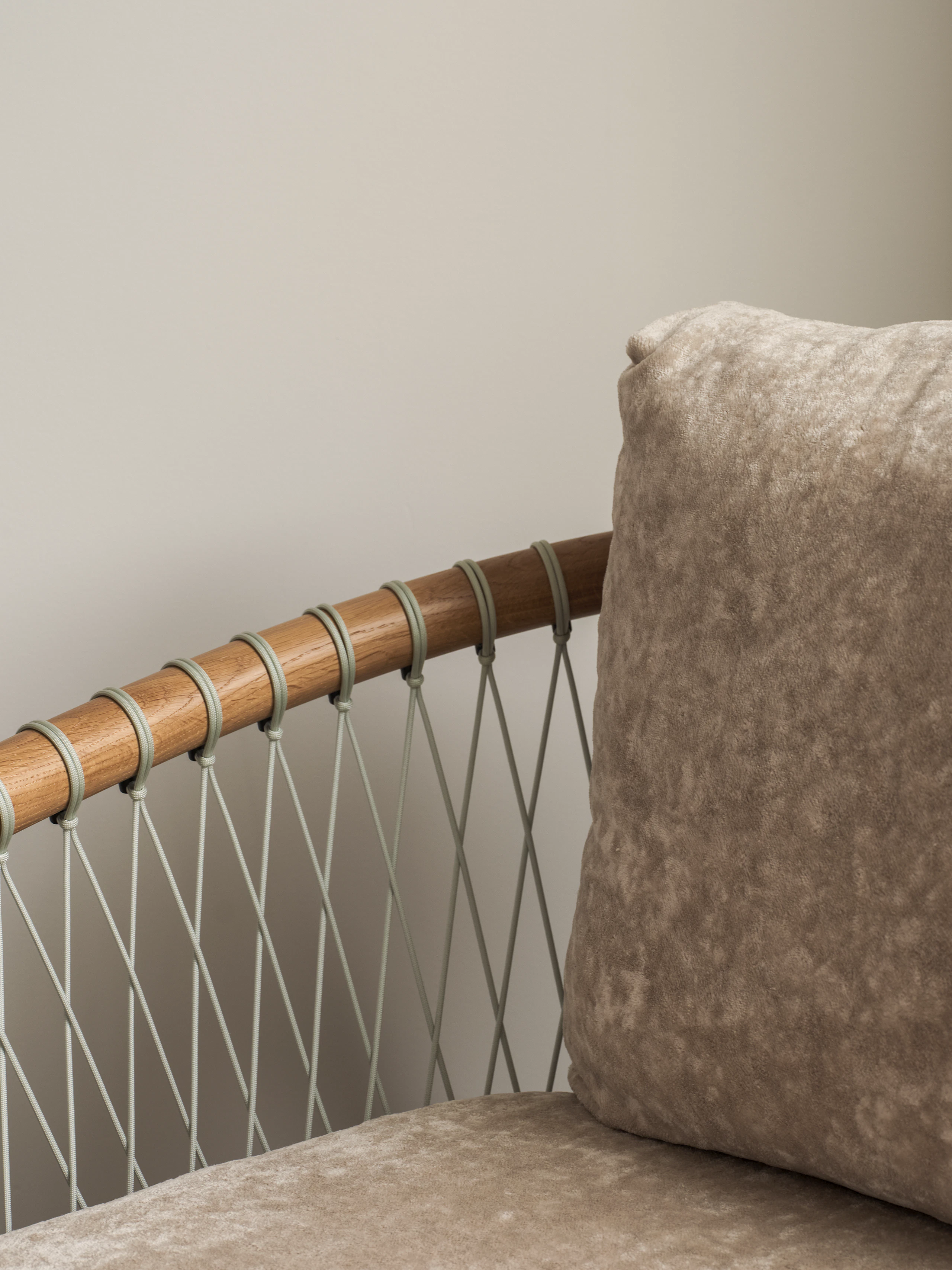 Detail view of a Crosshatch Chair arm, back, and seat, with a Natural Oak frame and grey parachute cords, upholstered with Linen Velvet in Obelisk, viewed at an angle.