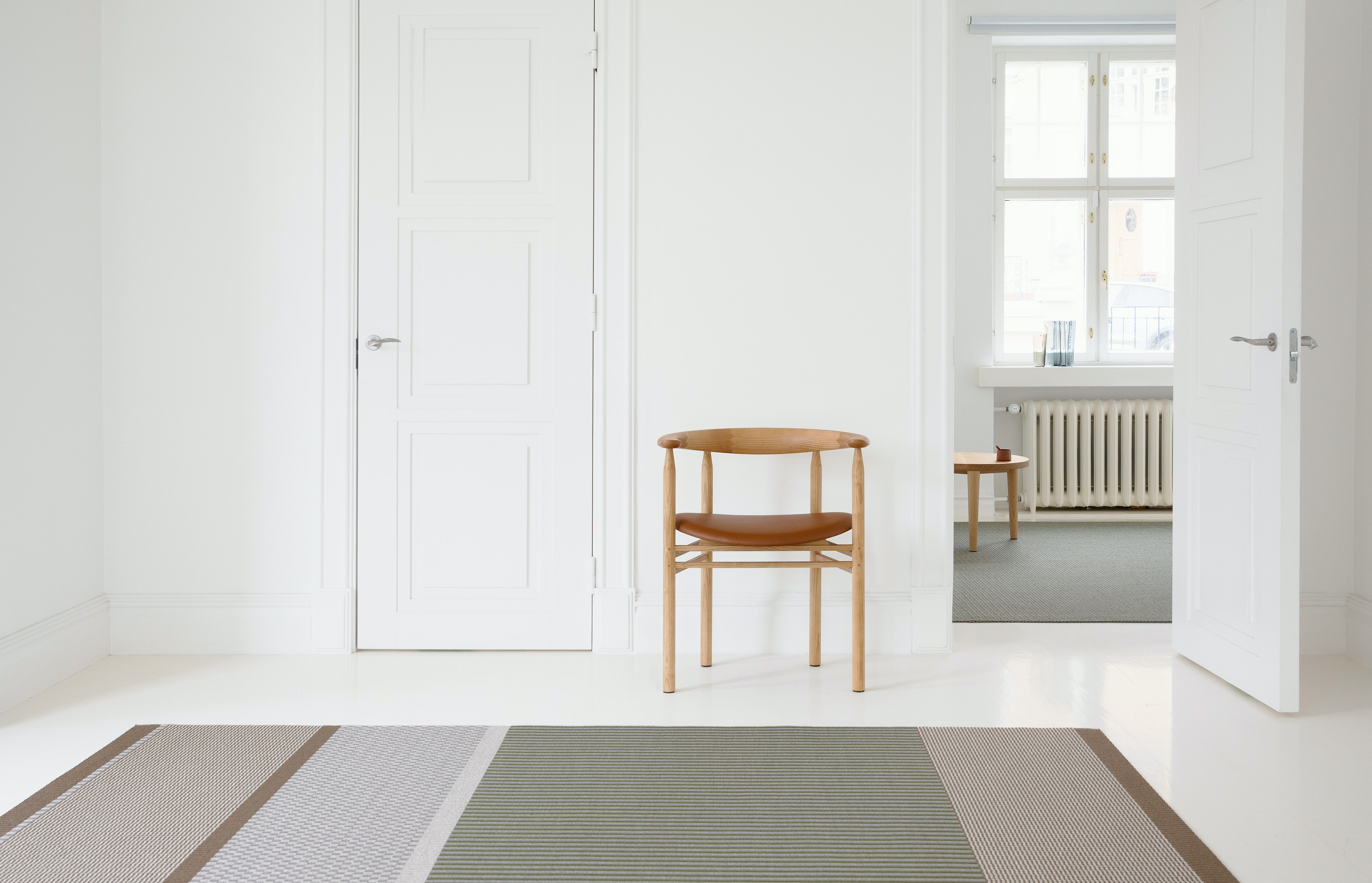 San Francisco Paper Yarn Rug on a living room floor with an armchair in the background