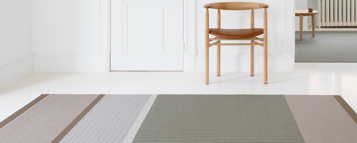 San Francisco Paper Yarn Rug on a living room floor with an armchair in the background