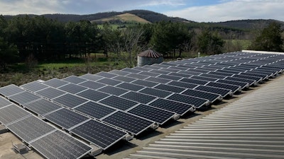 Solar panels installed on a roof, with a natural landscape in the background.
