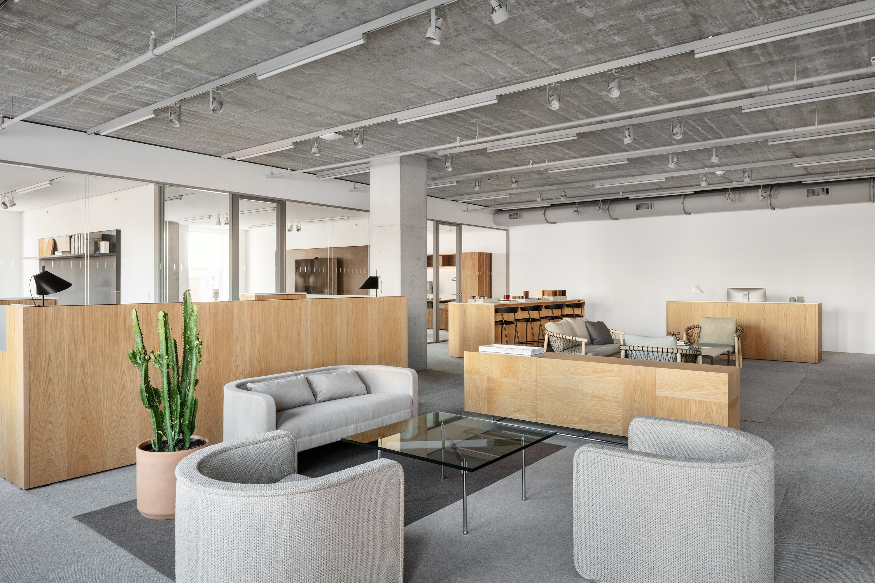 A neutral-toned lobby with gray U-Series Lounge Chairs and U-Series Lounge Sofa and a glass-topped Claw Table.