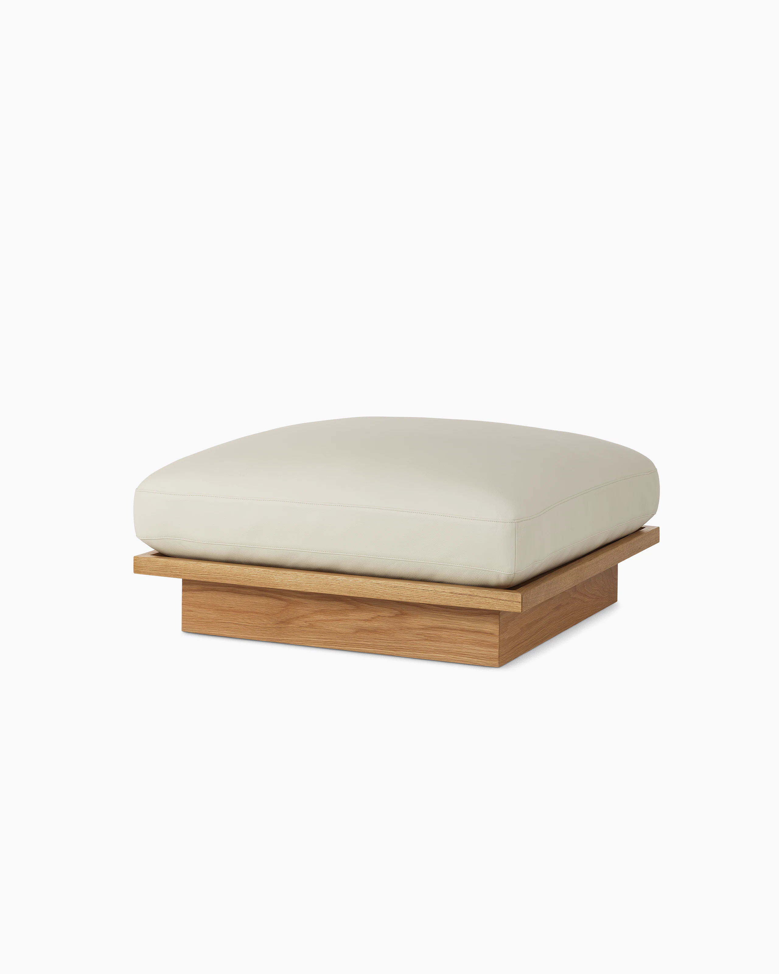 Pawson Drift Ottoman with white leather upholstery and white oak base, viewed from an angle.