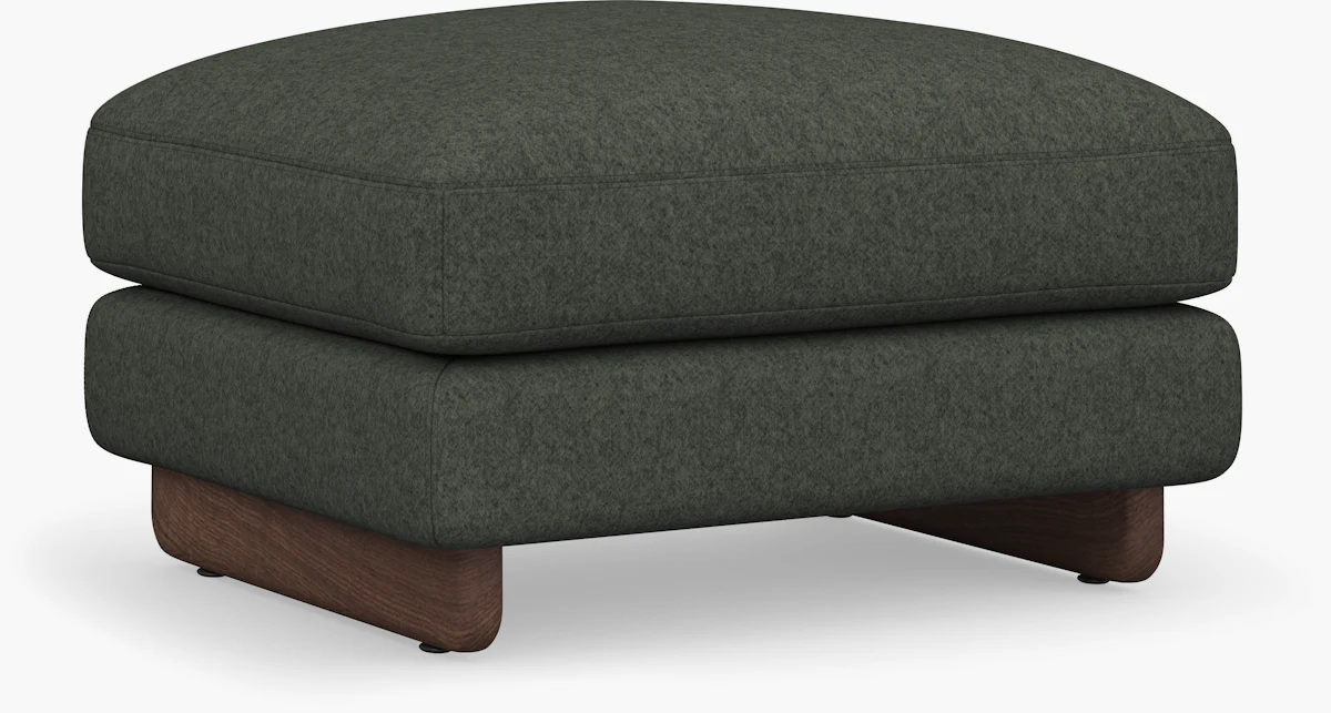 Close-up side view of dark green ottoman with wooden base.