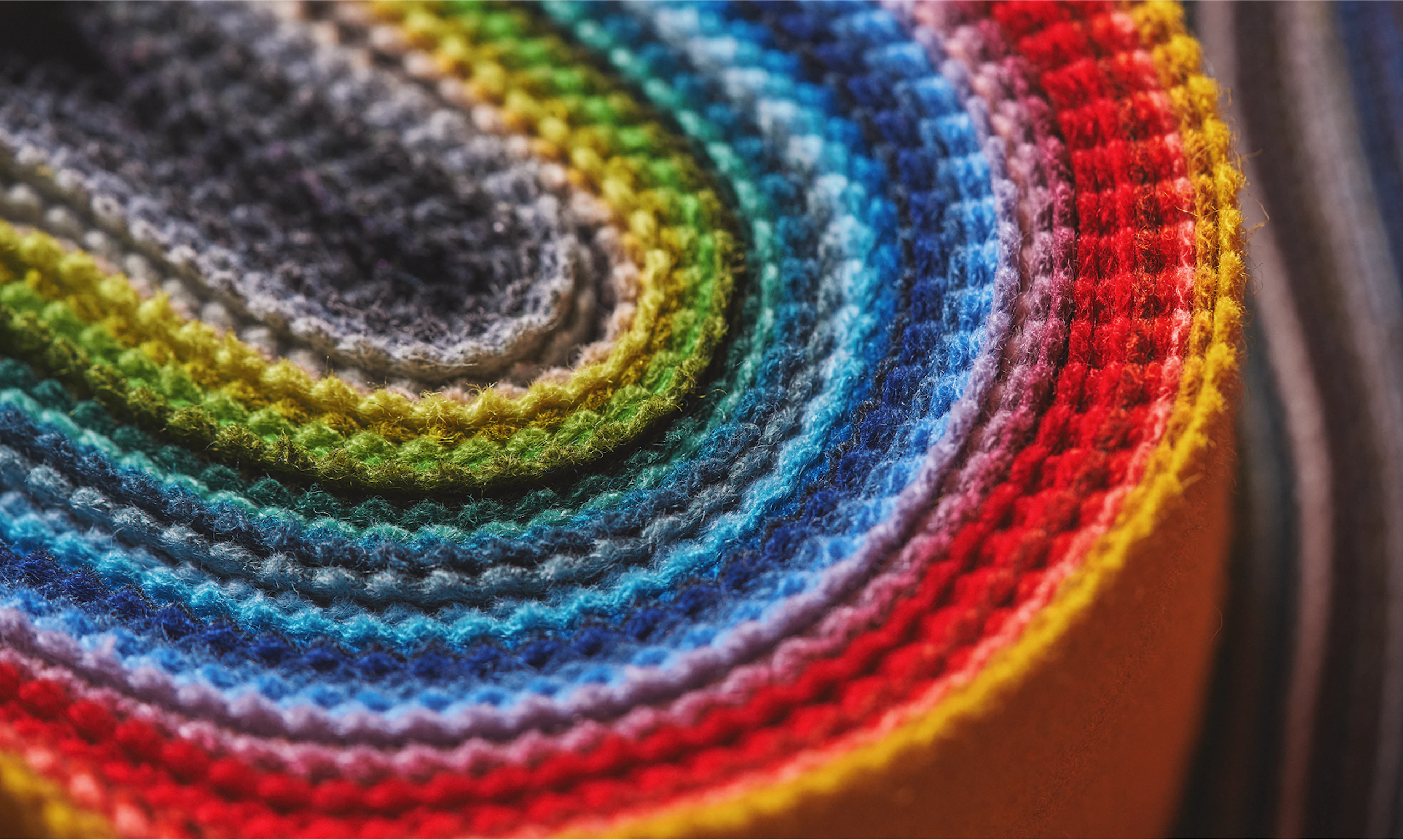 A bright range of colorful fabrics stacked on top of each other and folded into a U-shape.