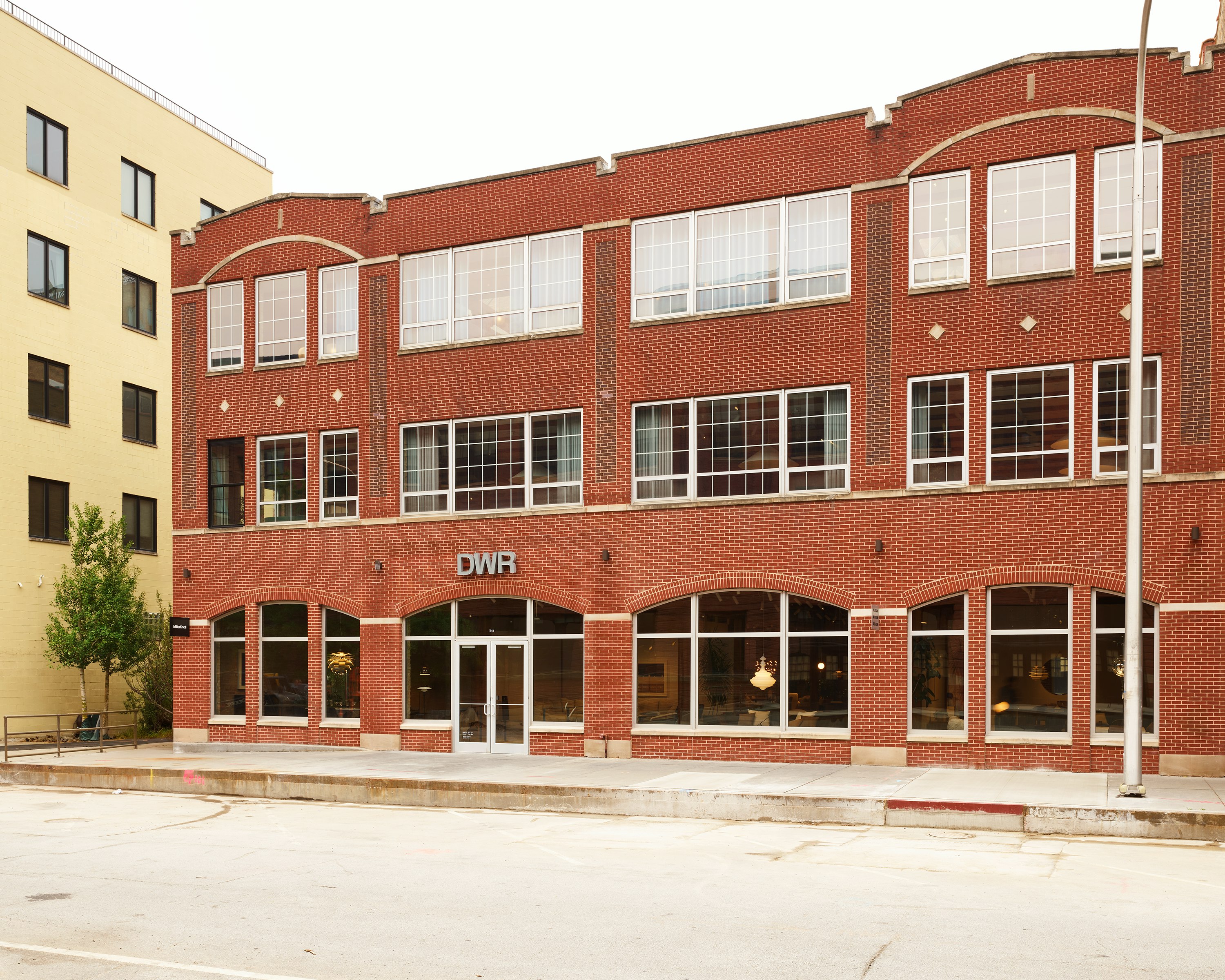 Exterior view of the MillerKnoll showroom, a red brick building with large windows, at 1144 W. Fulton Market in Chicago.