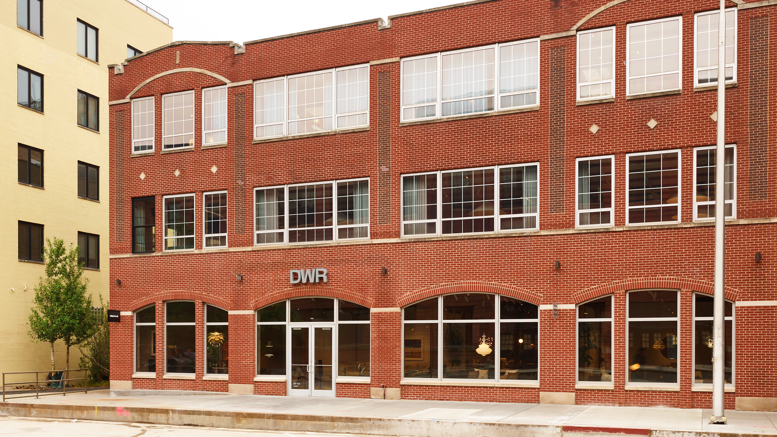 Exterior view of the MillerKnoll showroom, a red brick building with large windows, at 1144 W. Fulton Market in Chicago.