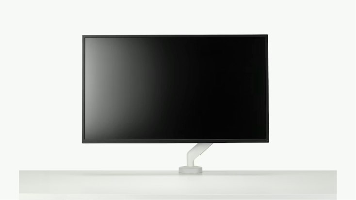 Black computer monitor mounted on a white Flo X Single Monitor Arm by Herman Miller.