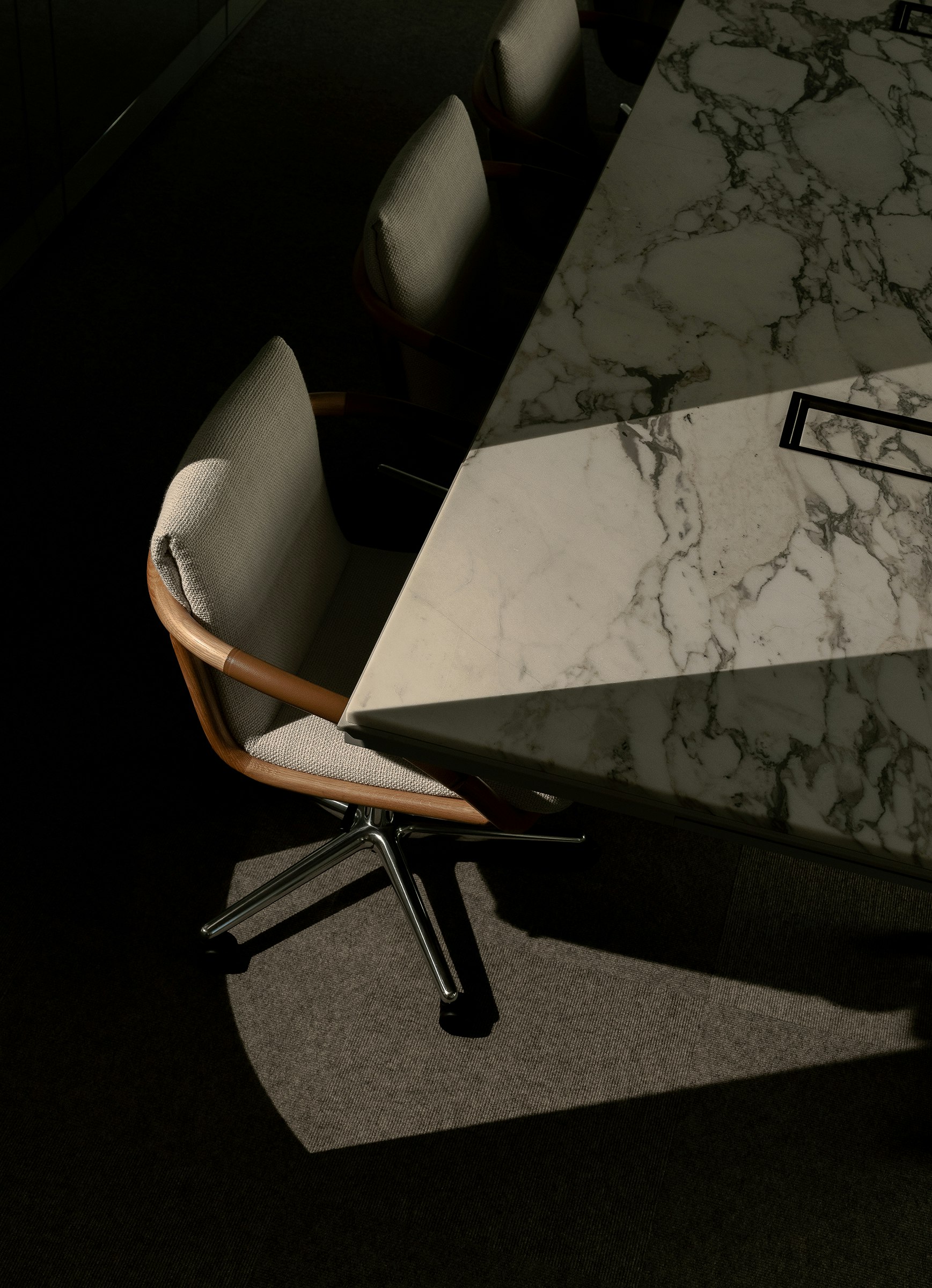 Full Loop Chair designed by EOOS with an Oak frame upholstered with Capri in Snow, with a Highline Conference Table with an Arabescato Corchia marble top, viewed from above at an angle.