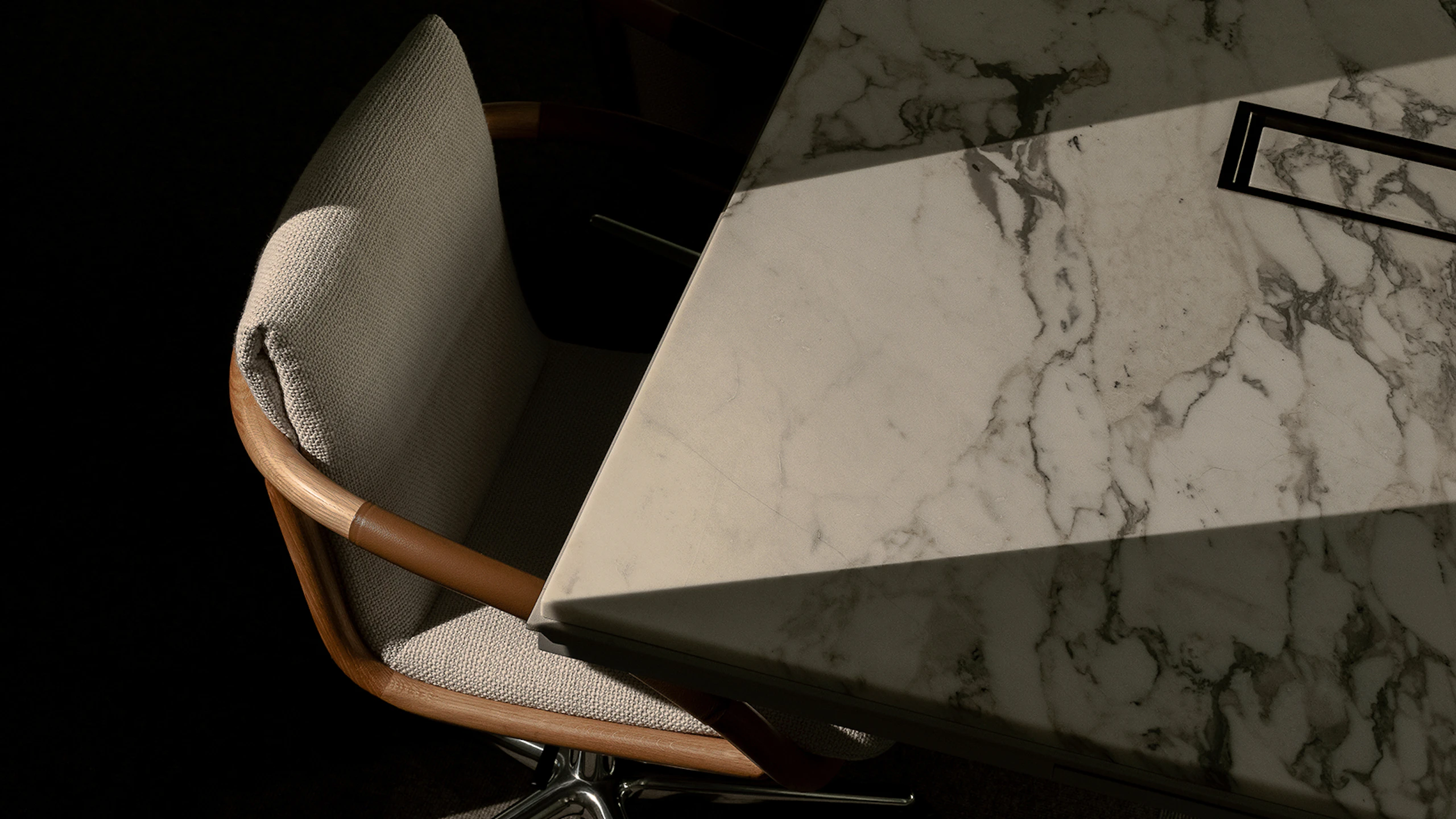 Full Loop Chair designed by EOOS with an Oak frame upholstered with Capri in Snow, with a Highline Conference Table with an Arabescato Corchia marble top, viewed from above at an angle.