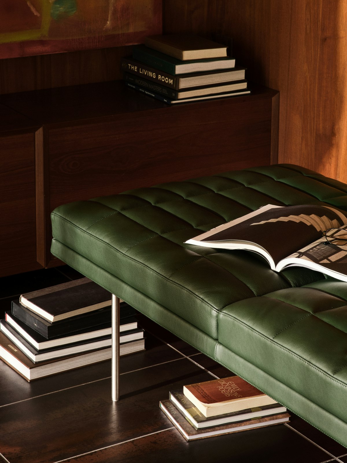 Tuxedo Component Bench designed by Bassam Fellows for Geiger in Prone Leather in Vine shown at an angle; styled with a variety of books.