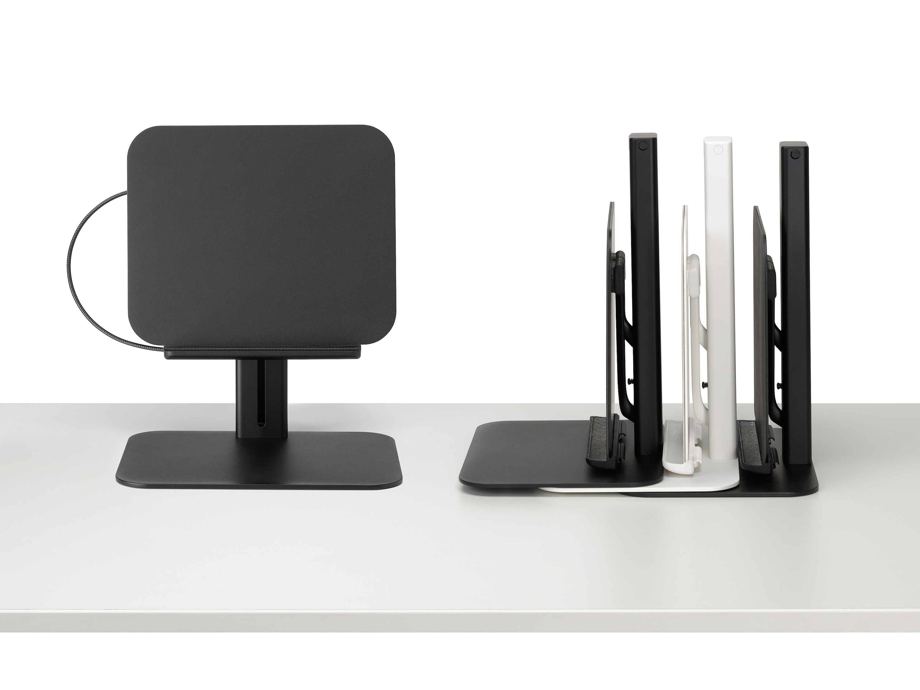 Lana laptop stand in black viewed from the front and a stack of black and white Lana laptop stands viewed from the side.