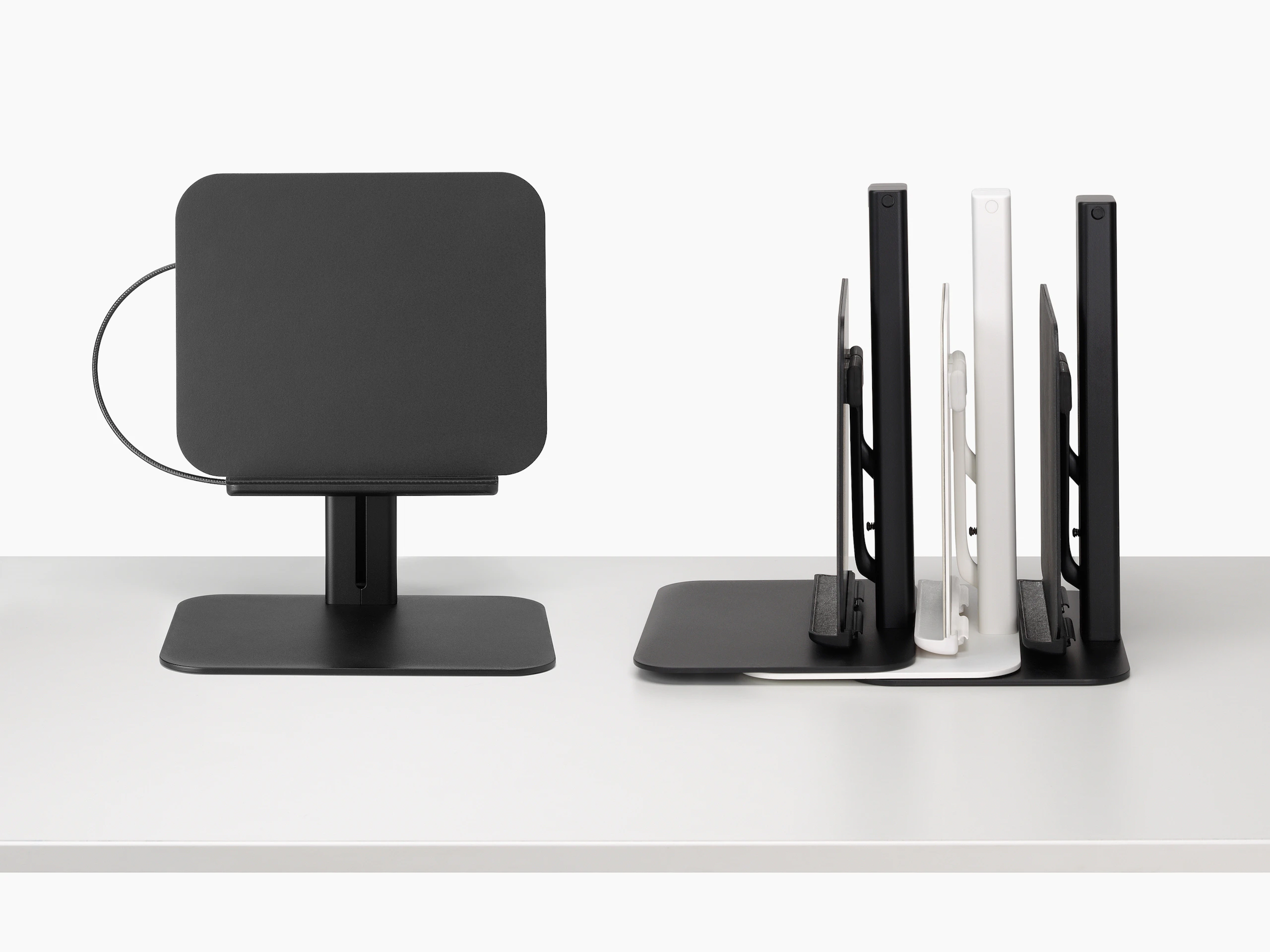 Lana laptop stand in black viewed from the front and a stack of black and white Lana laptop stands viewed from the side.
