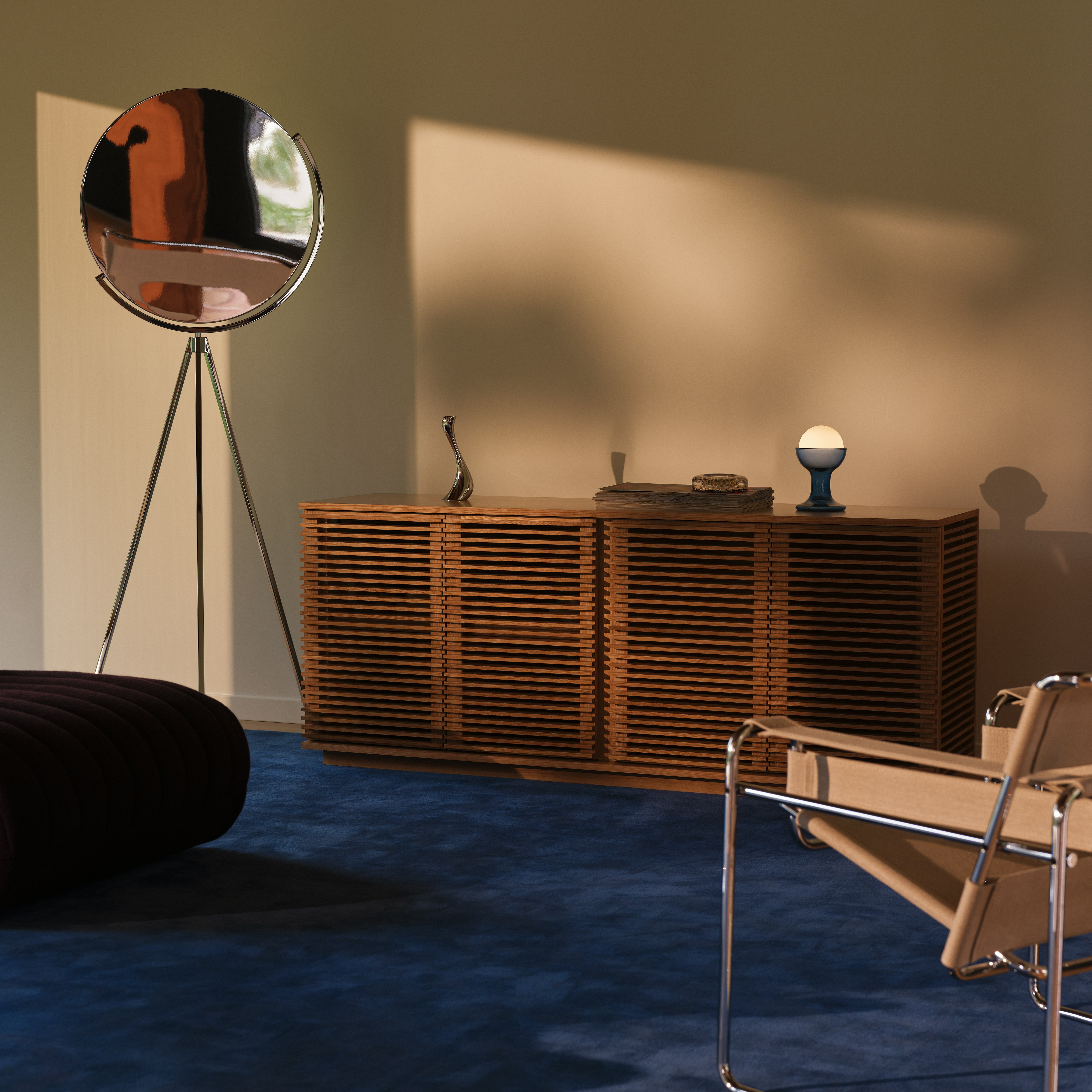 A Large Line Credenza in Oak with Superloon Lamp in Chrome on a Grand Rug in navy.
