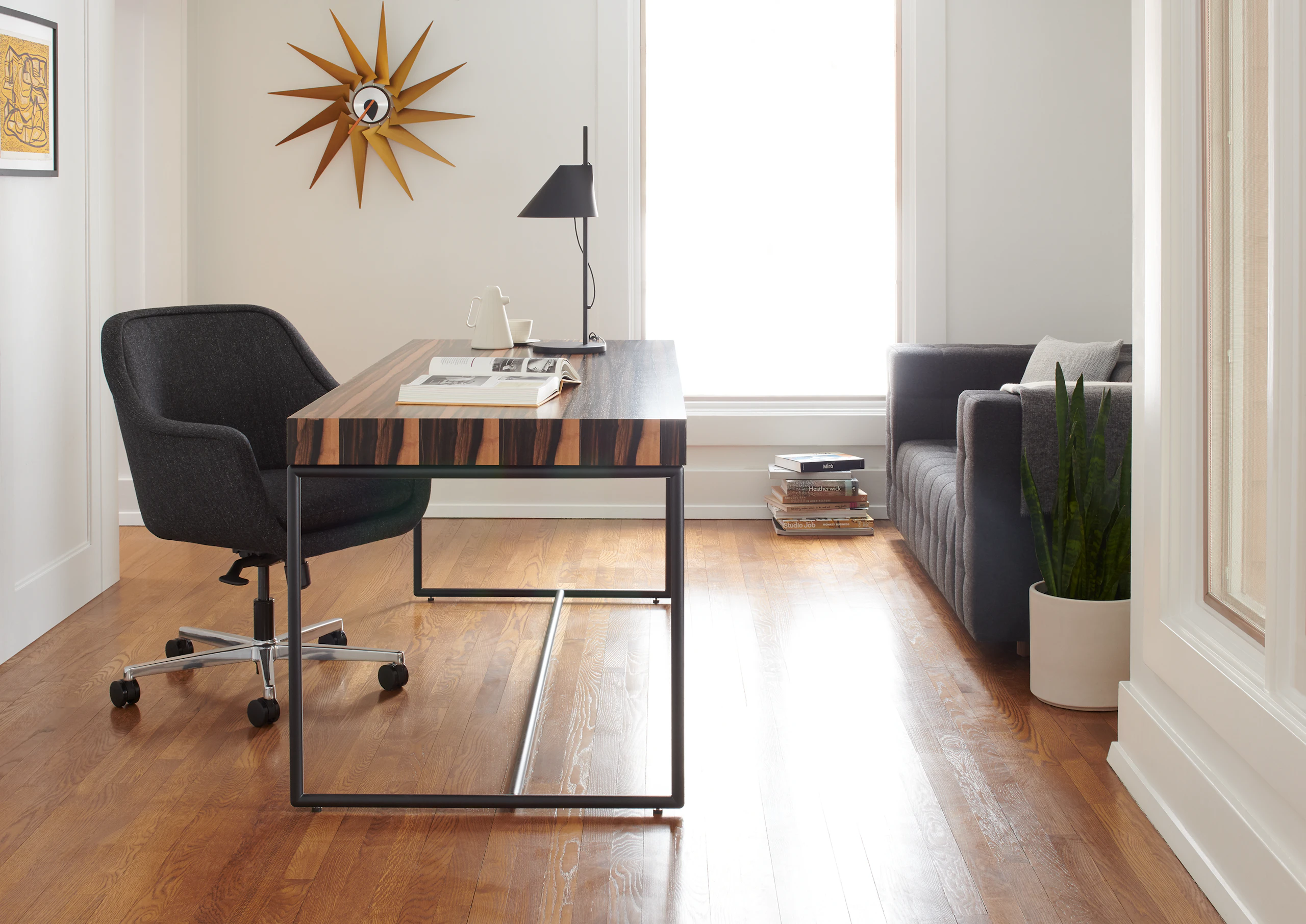A private office featuring a Domino Desk, a Bumper Chair, and Rapport Settee.