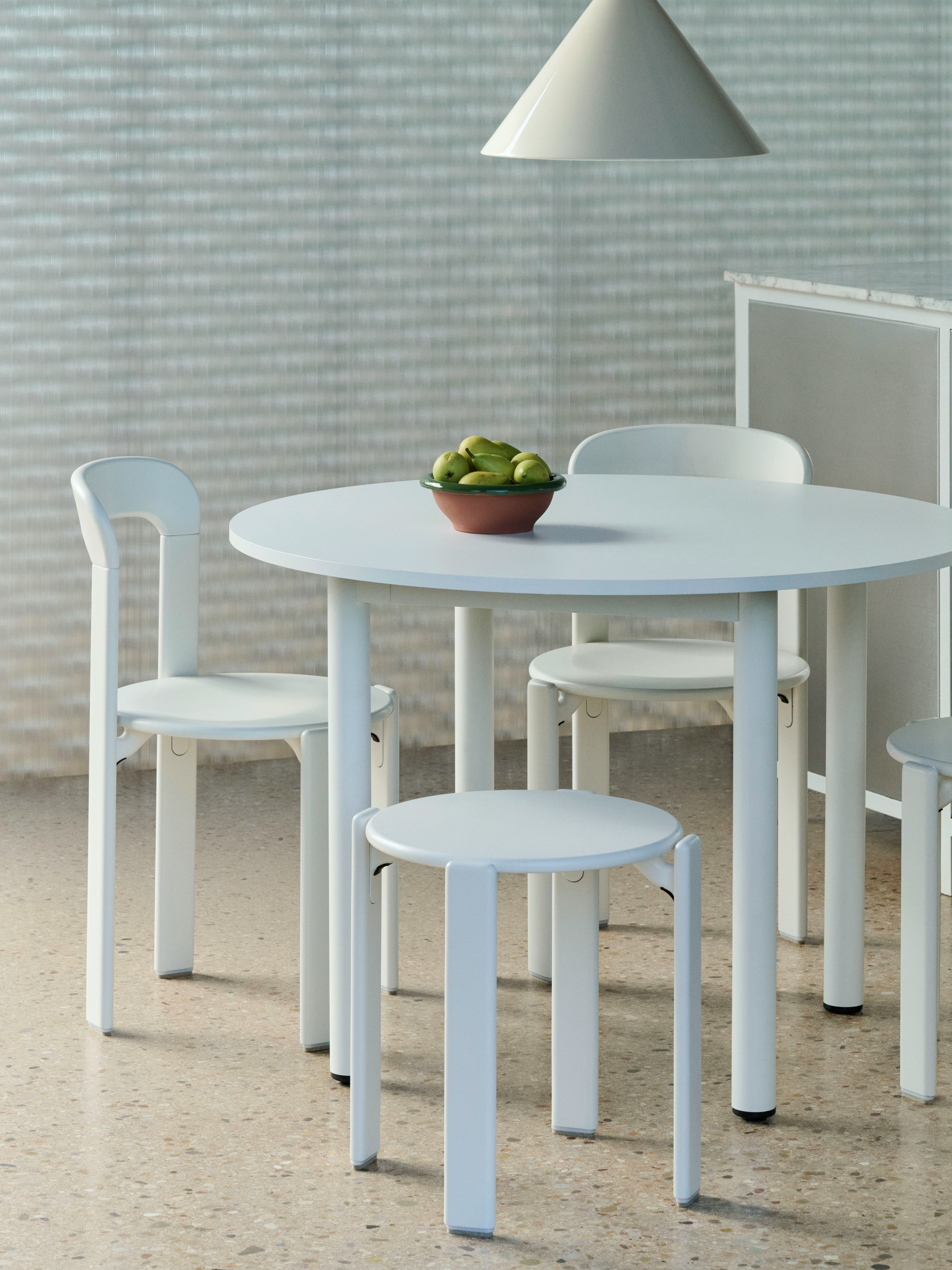 Annex round table in white finish surrounded by white Rey Chairs and Stools, shown in a light and minimal setting.