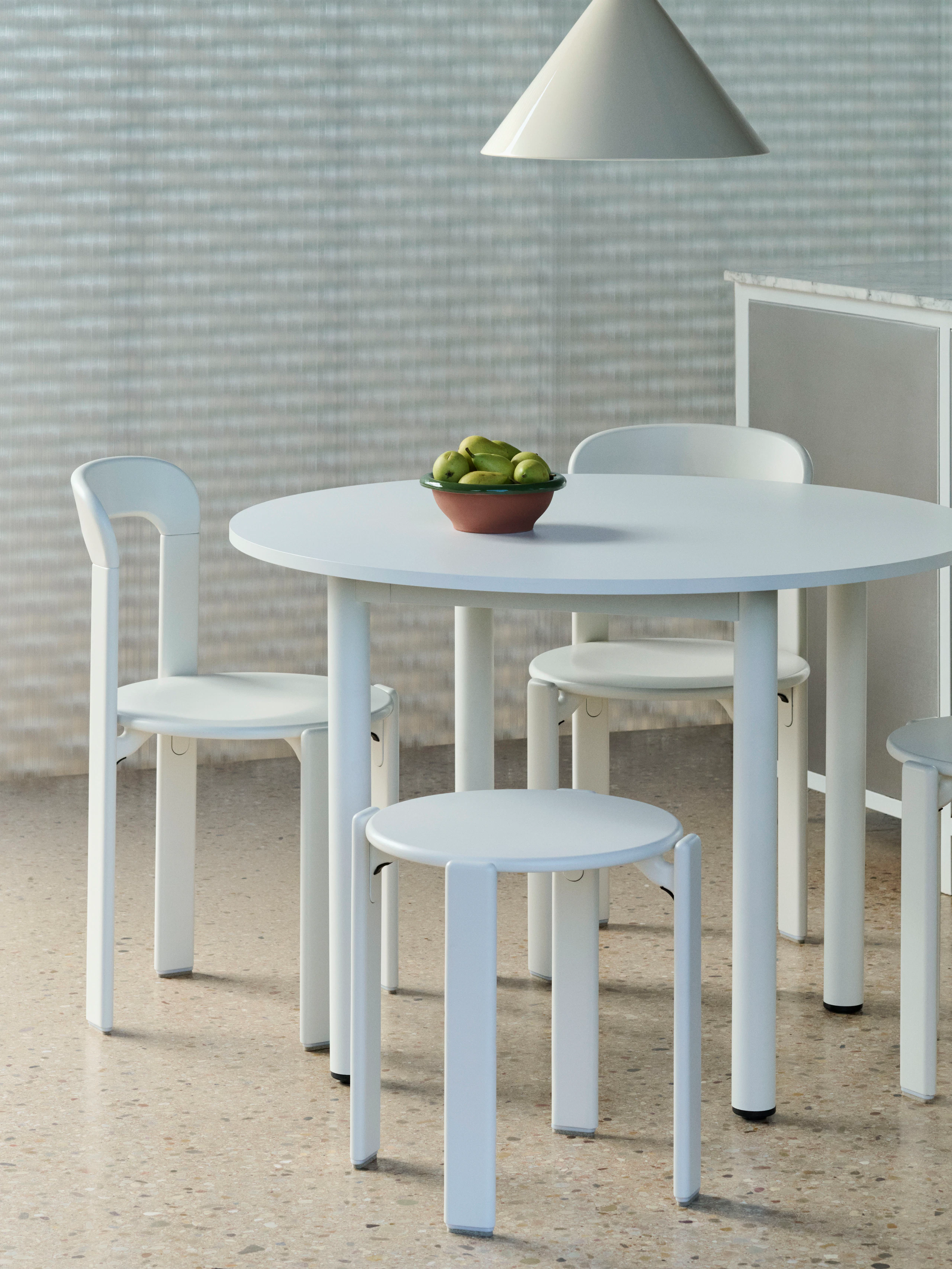 Annex round table in white finish surrounded by white Rey Chairs and Stools, shown in a light and minimal setting.
