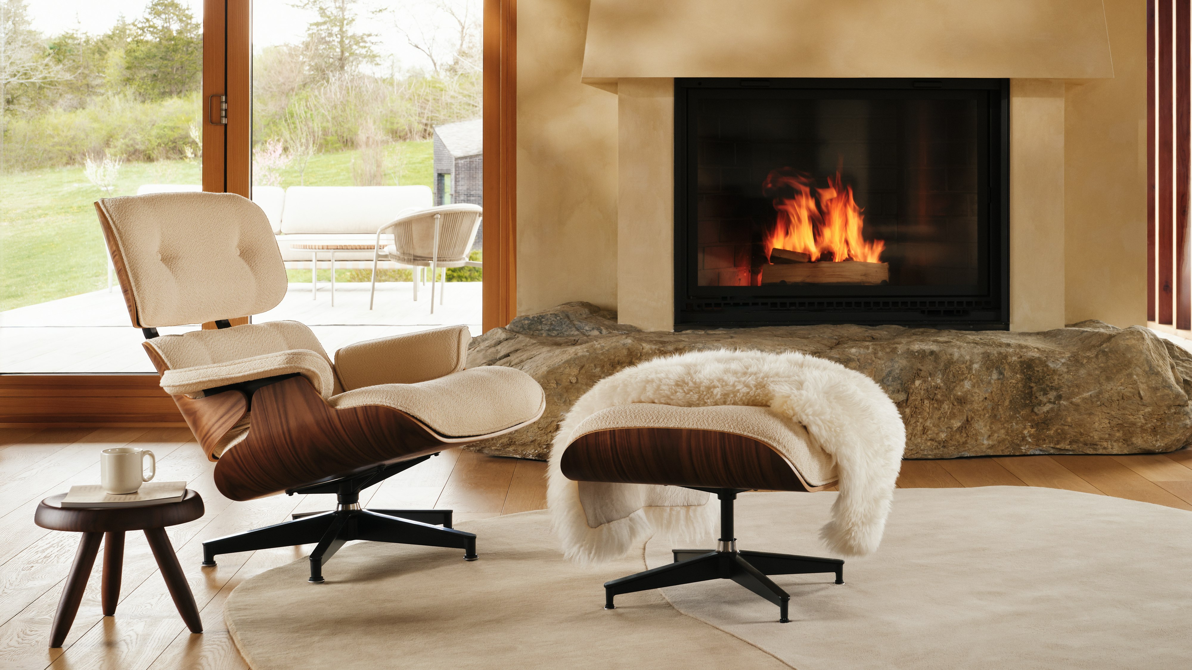Eames Lounge and Ottoman in Cream boucle in front of a fireplace