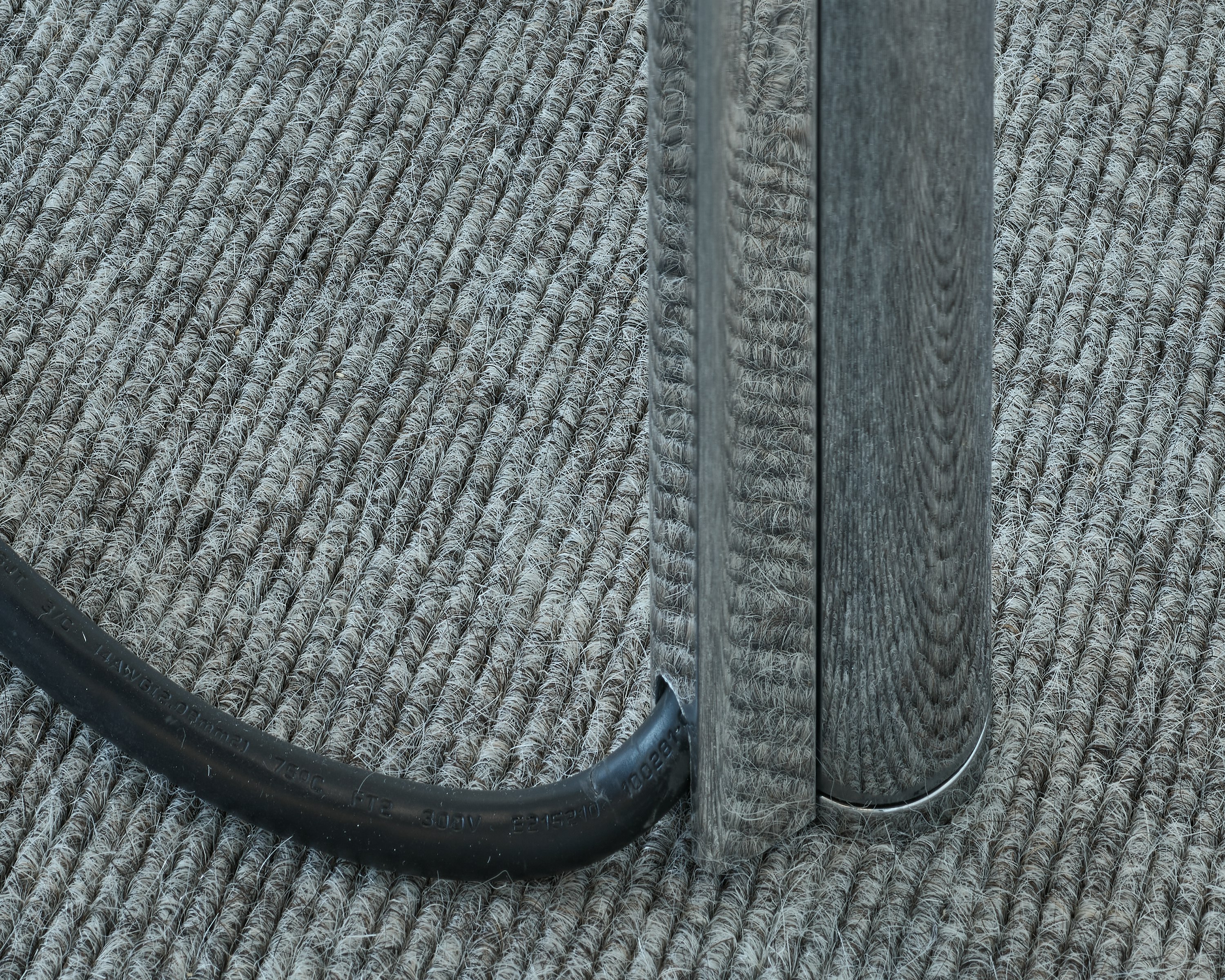 Detail view of a Parsons Table leg in chrome with a wire coming out, displaying cable management capabilities, viewed from above at an angle.