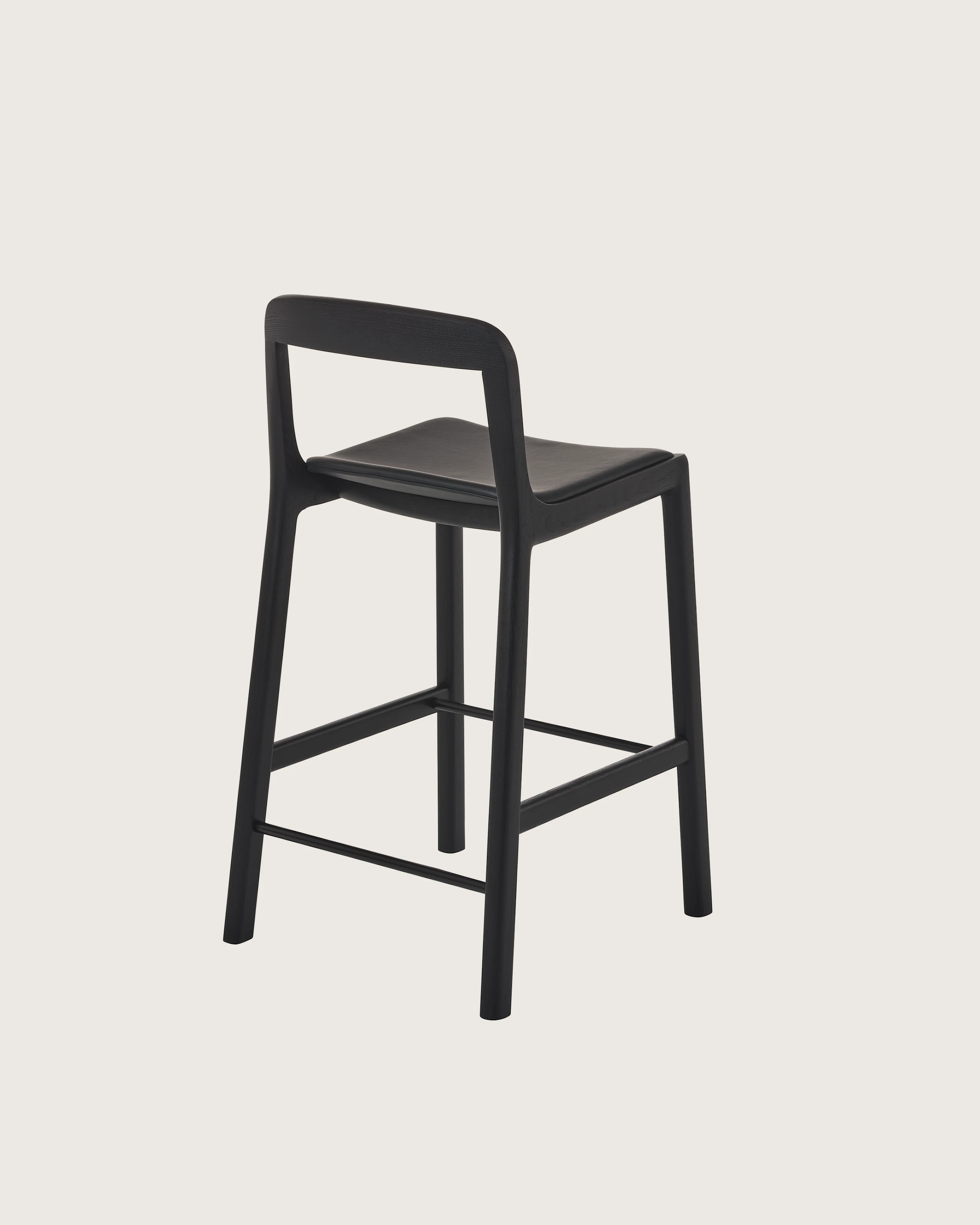 Lijn Stool by Carole Baijings for Geiger in Ebonized Oak frame upholstered with Maharam Prone Leather in Obsidian, angled back view on a white sweep.