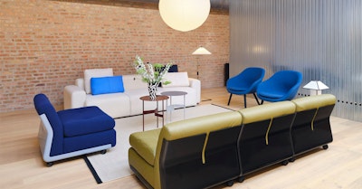A white sofa, bright blue chairs, and a green sofa from HAY decorate this communal seating area at MillerKnoll Design Days
