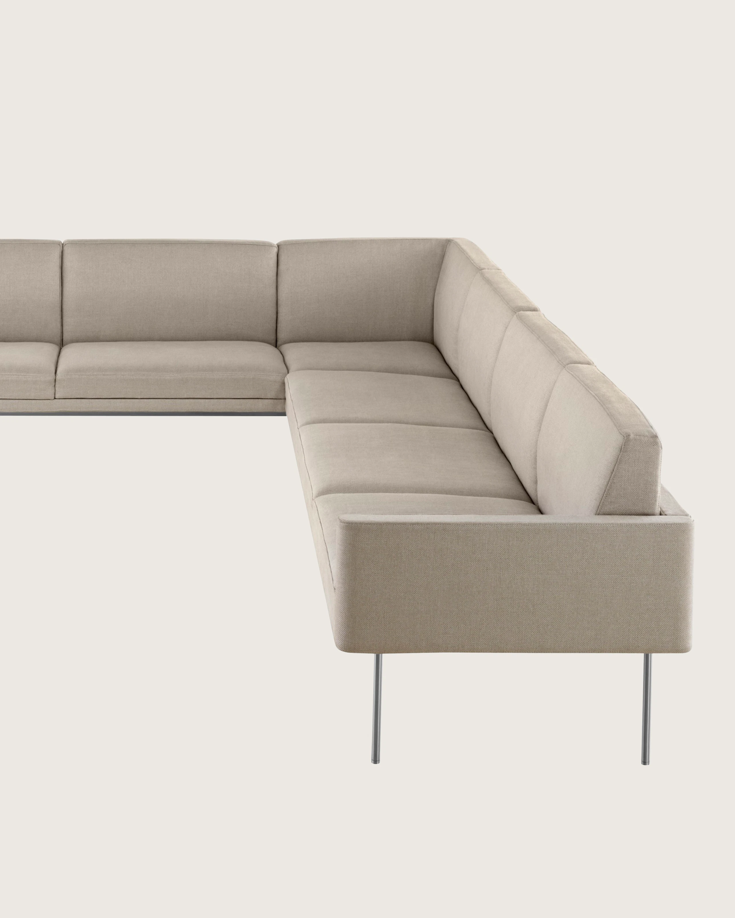 Partial view of a non-quilted Tuxedo Component corner unit upholstered in beige fabric.