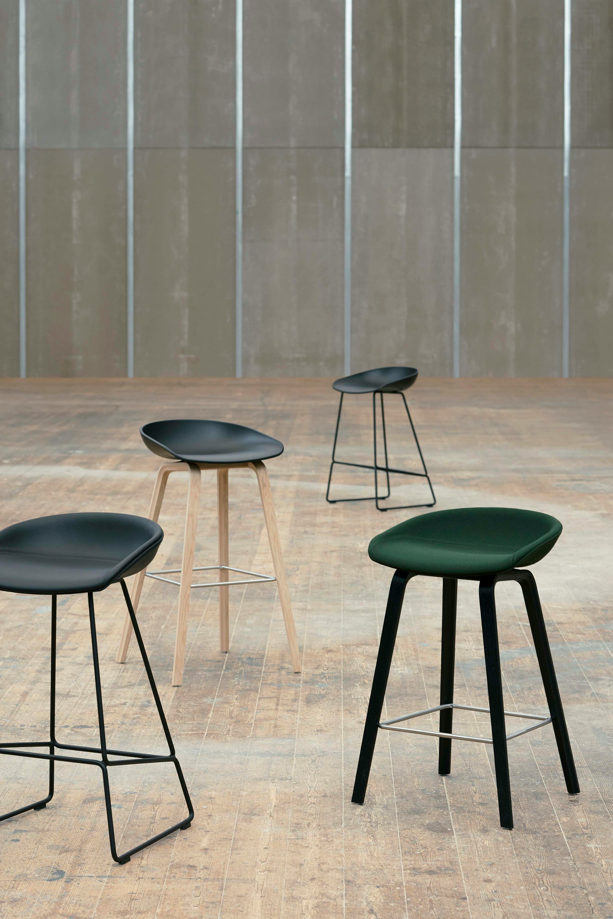 Four different About A Stool variations arranged in large empty room.