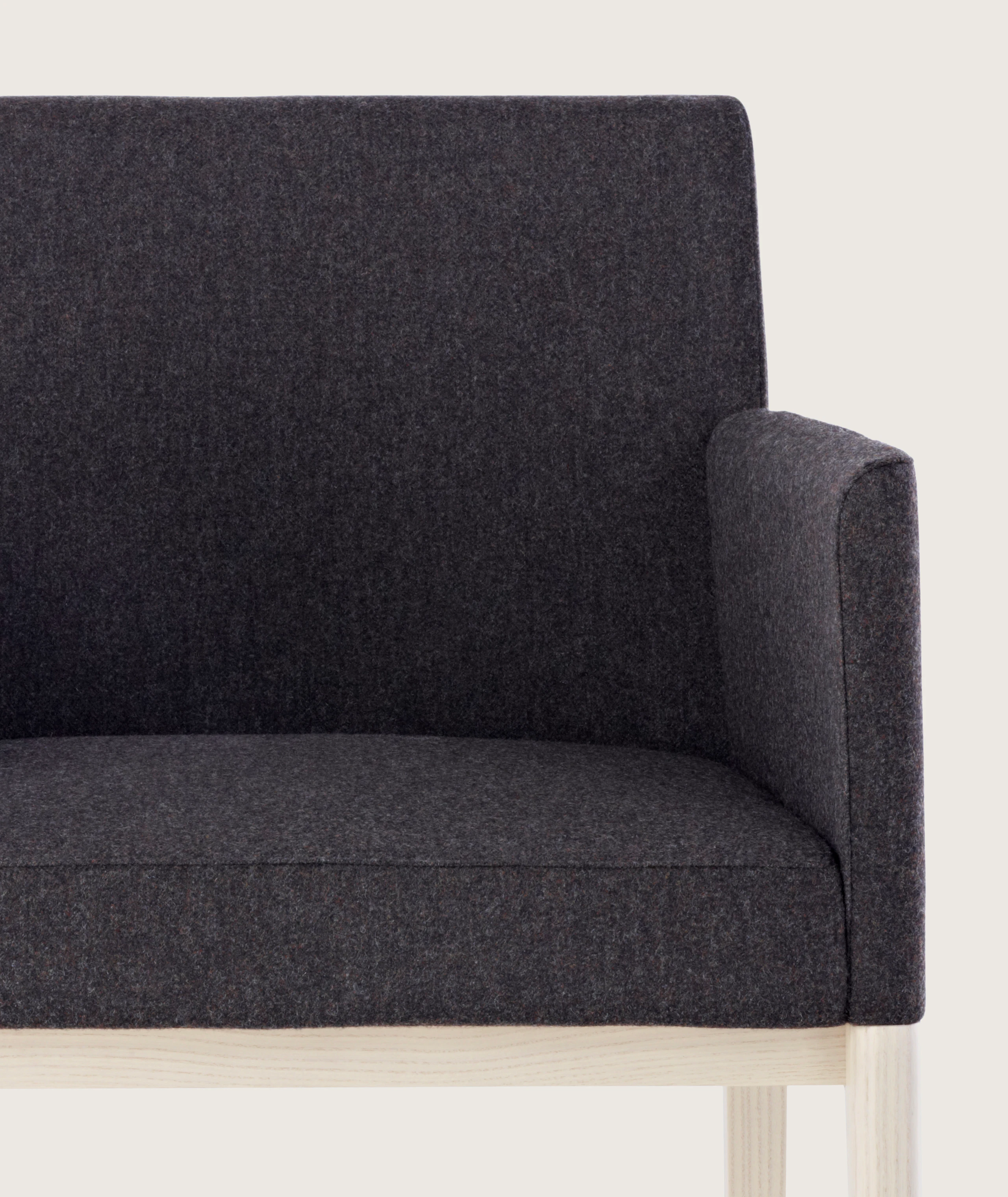 Side view of a Nessel side chair with black fabric upholstery, wraparound arms, and a wood frame with a light finish.