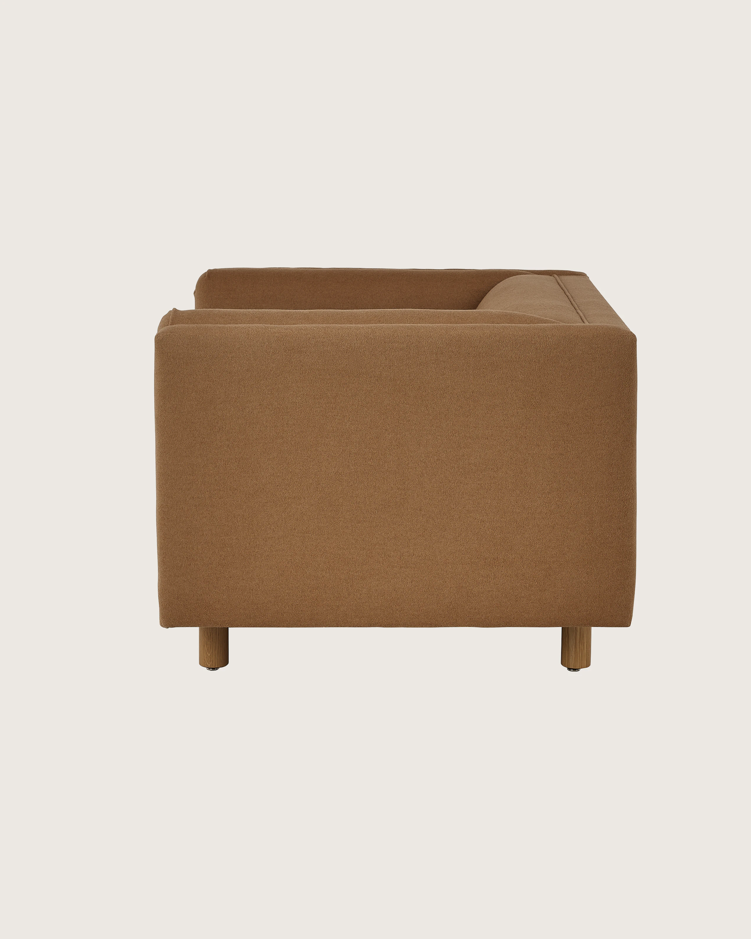 Rolled Arm Club Chair designed by Ward Bennett upholstered in Brushed Camel in Natural with a Natural Oak base, shown in profile on a white sweep.