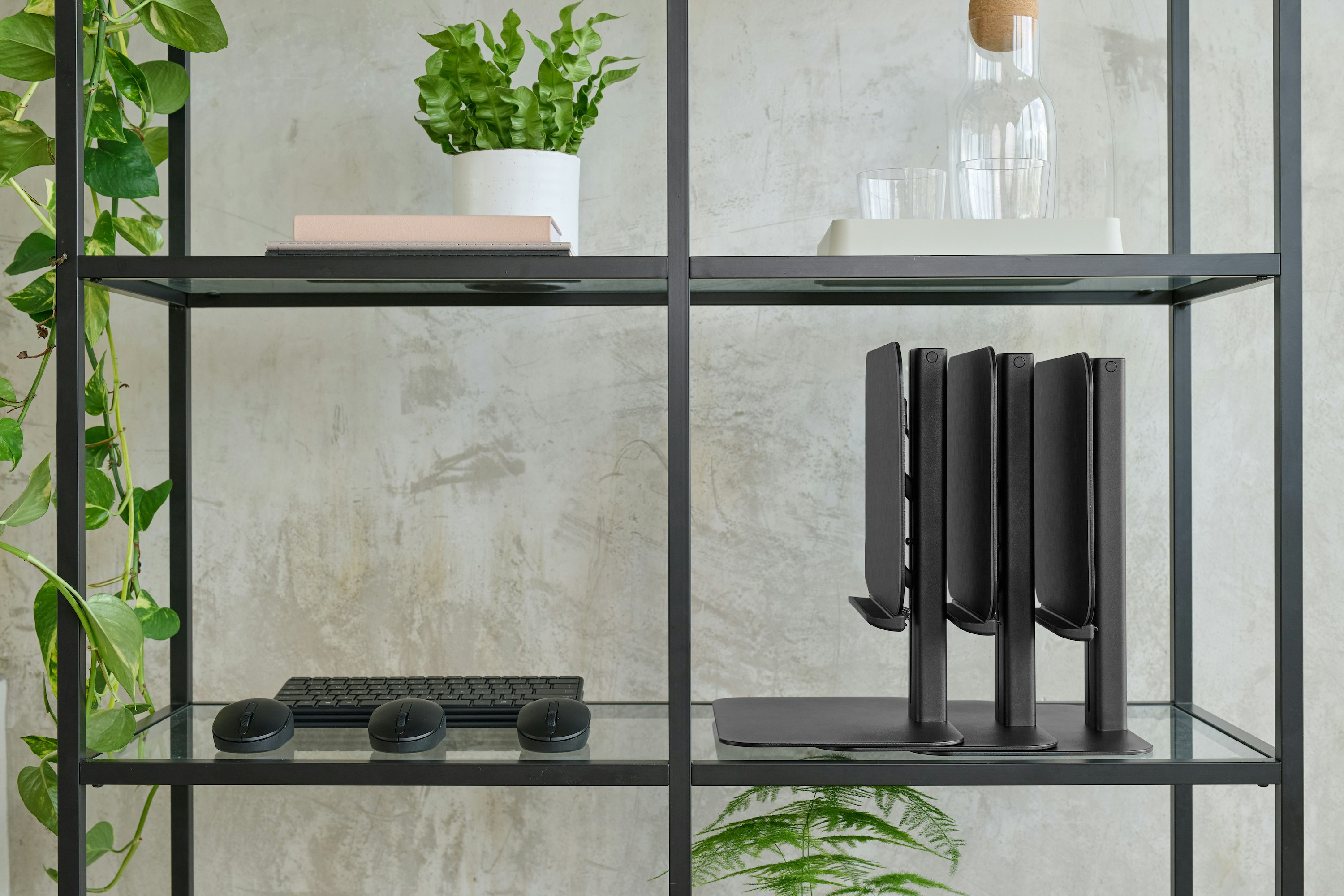 Three black Lana laptop stands in a folded position on a shelf.