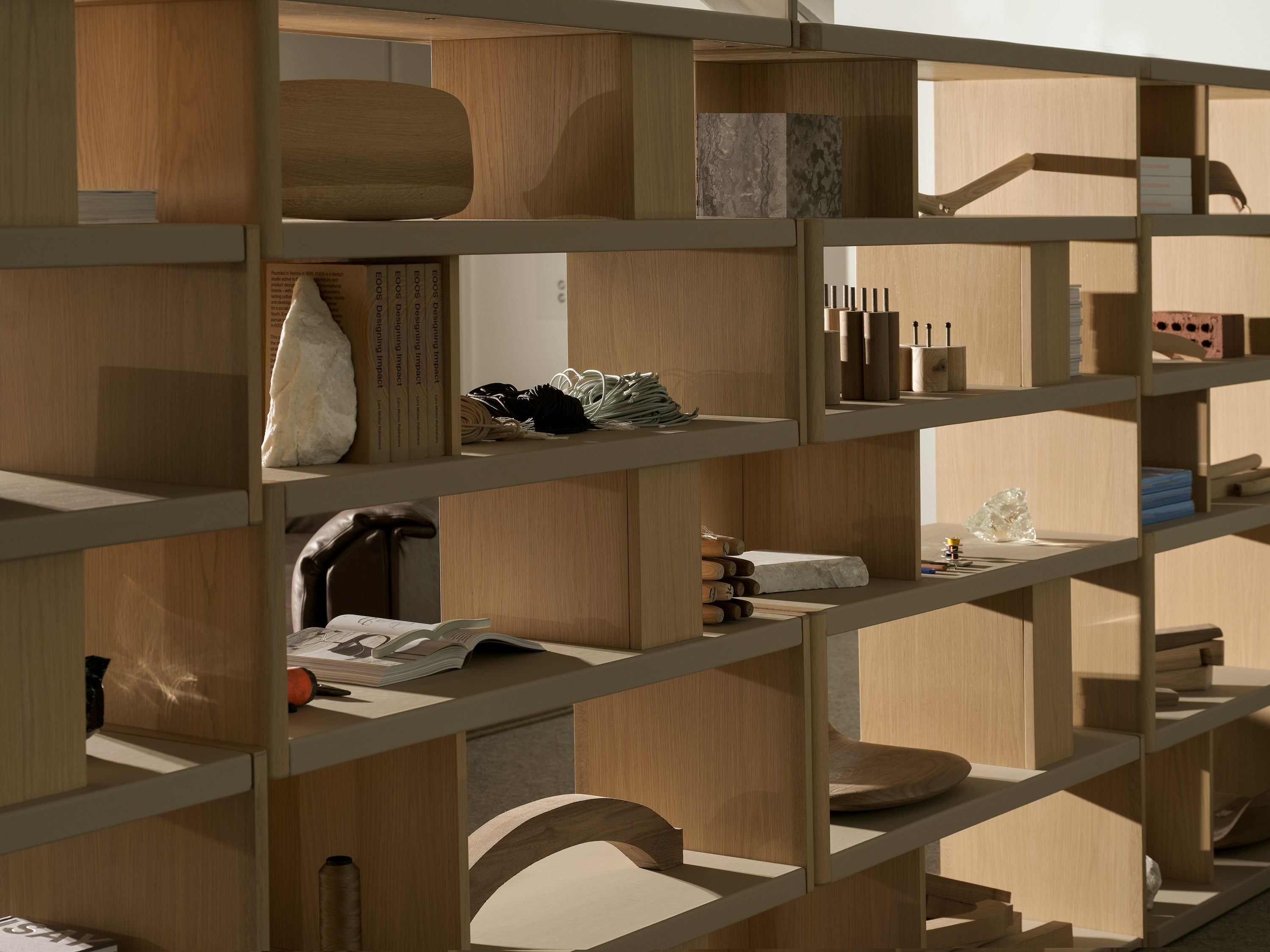 Various New Canaan Tall Bookshelves in Light Oak wrapped with Bristol Leather in Champagne arranged side by side and styled with various objects, viewed at an angle.