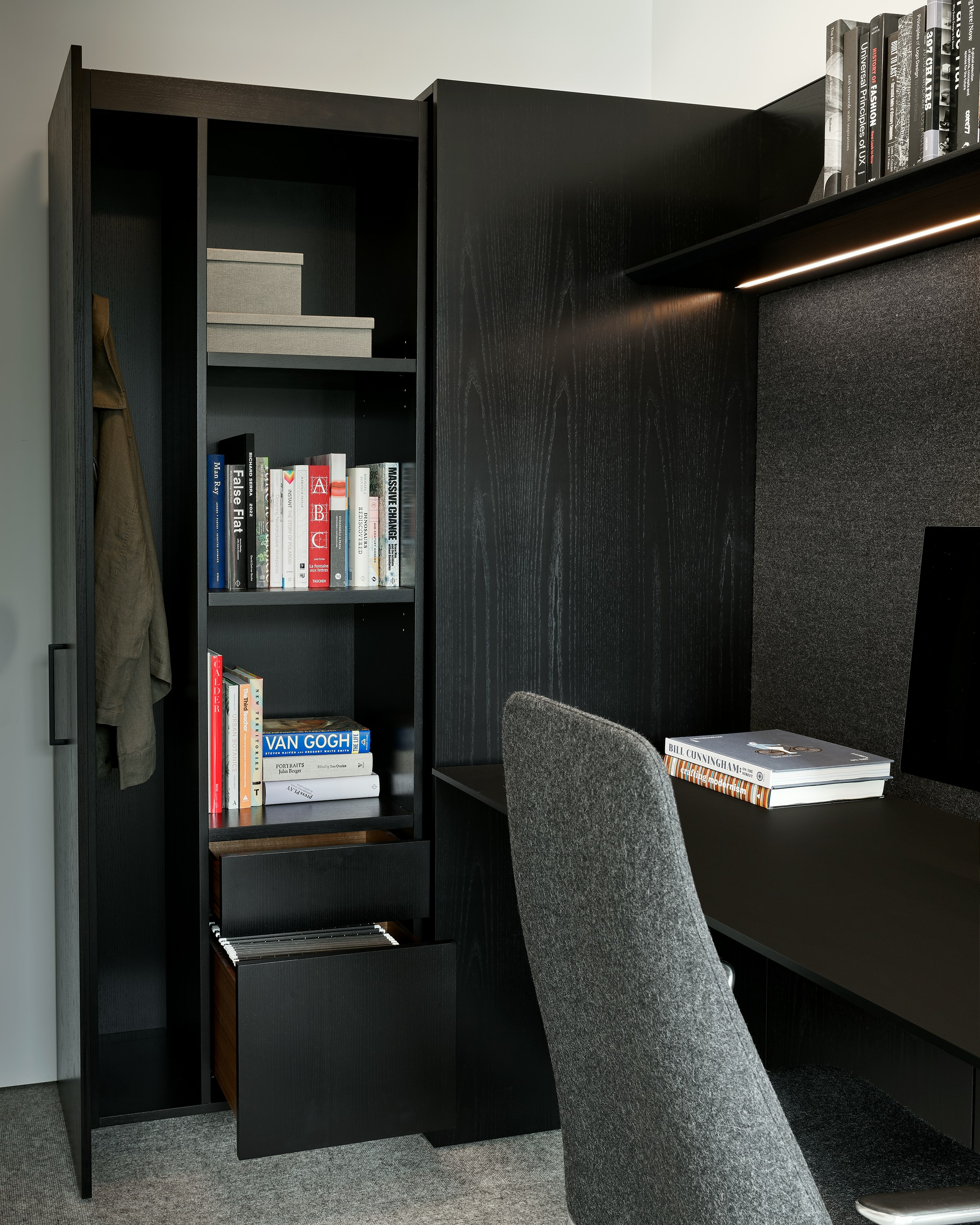 Geiger One Casegoods Private Office open vertical pull-out wardrobe in Ebonized Flat Cut Ash, viewed at an angle in a private office setting.