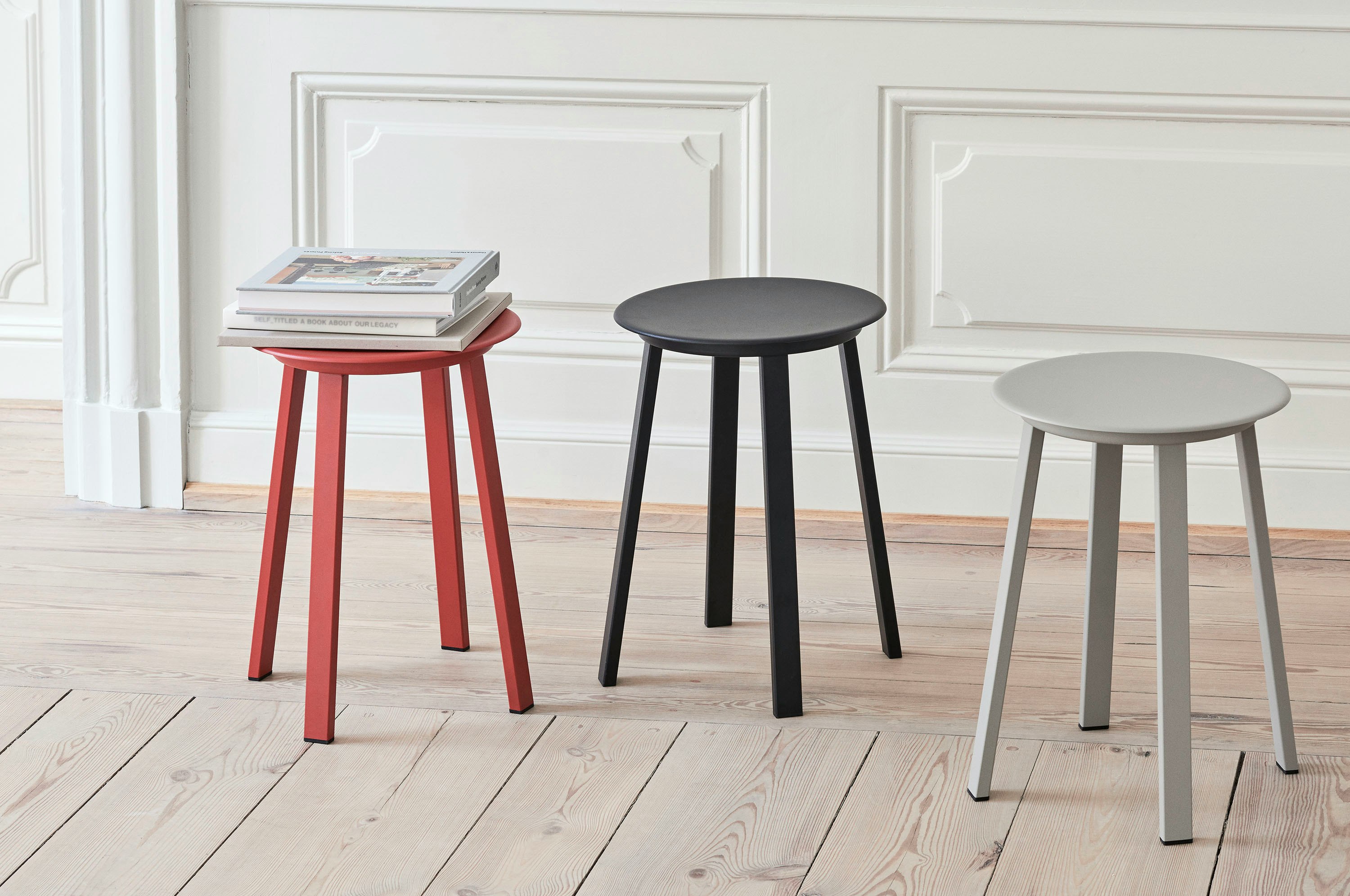 Red, black, and grey Revolver Stools arranged near a wall.