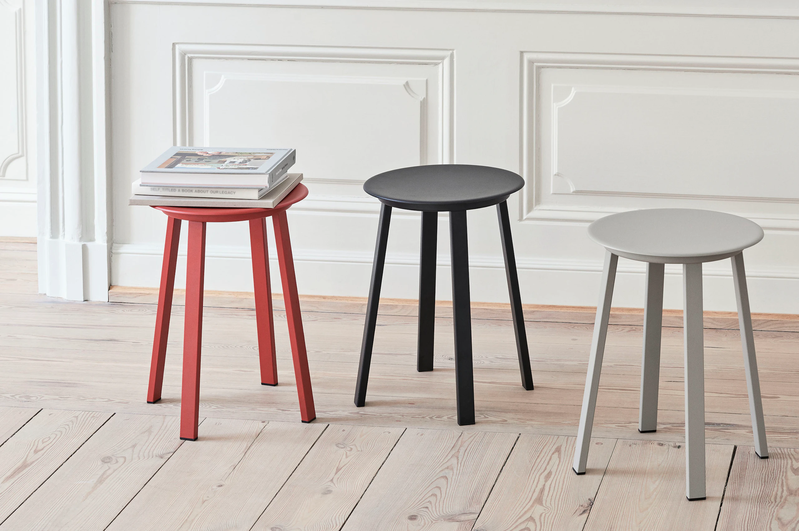Red, black, and grey Revolver Stools arranged near a wall.