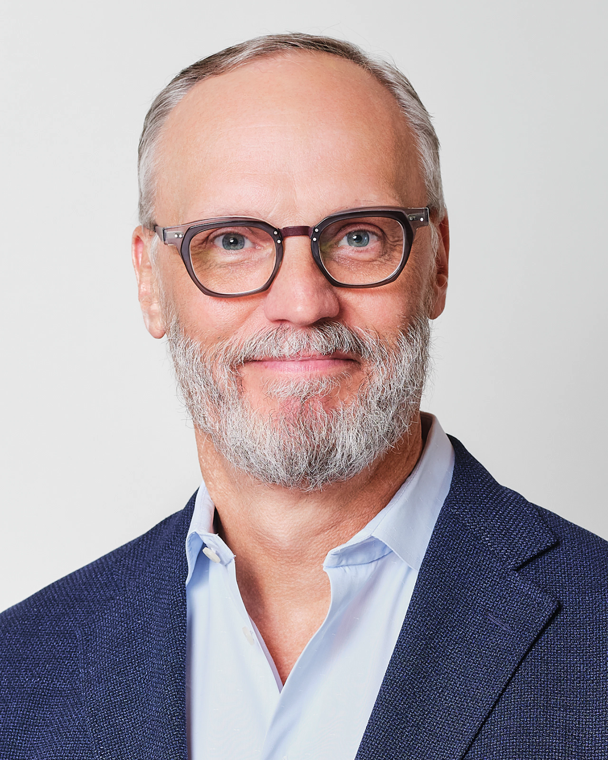 Jeff Stutz, CEO of MillerKnoll, Inc., wearing a blue blazer and glasses.