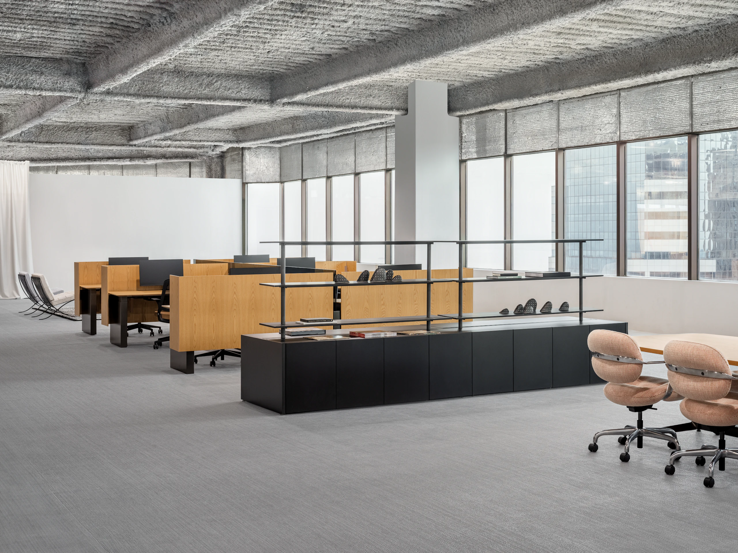 Various work settings in an open office are viewed in a large open room including a meeting table with chairs, shared storage with shelves, workstations and lounge seating.