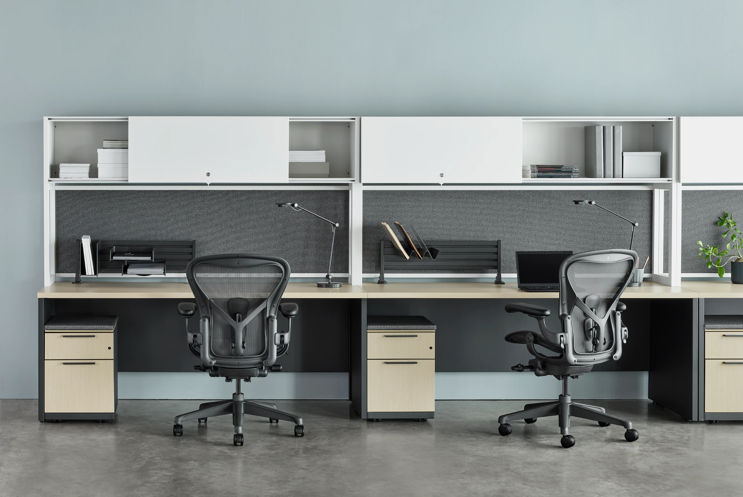 Two Canvas Metal Desks with white upper storage, grey tackboards, and grey Aeron Chairs.