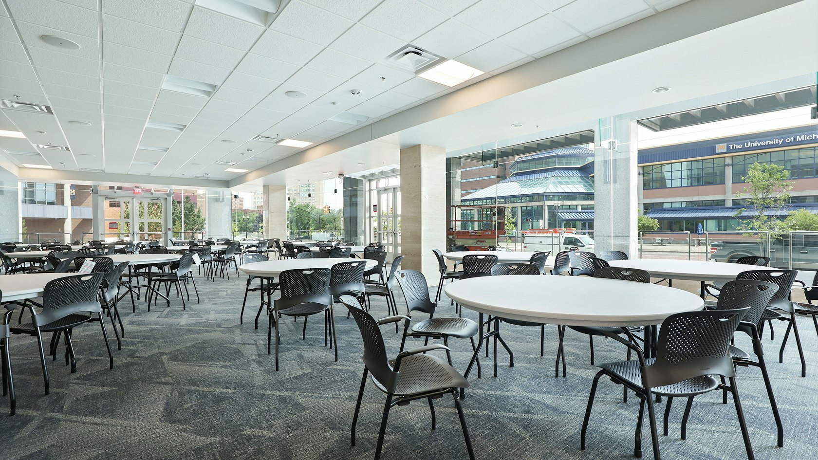 Large communal seating area furnished with white round tables with black Caper Stacking Chairs by Herman Miller.