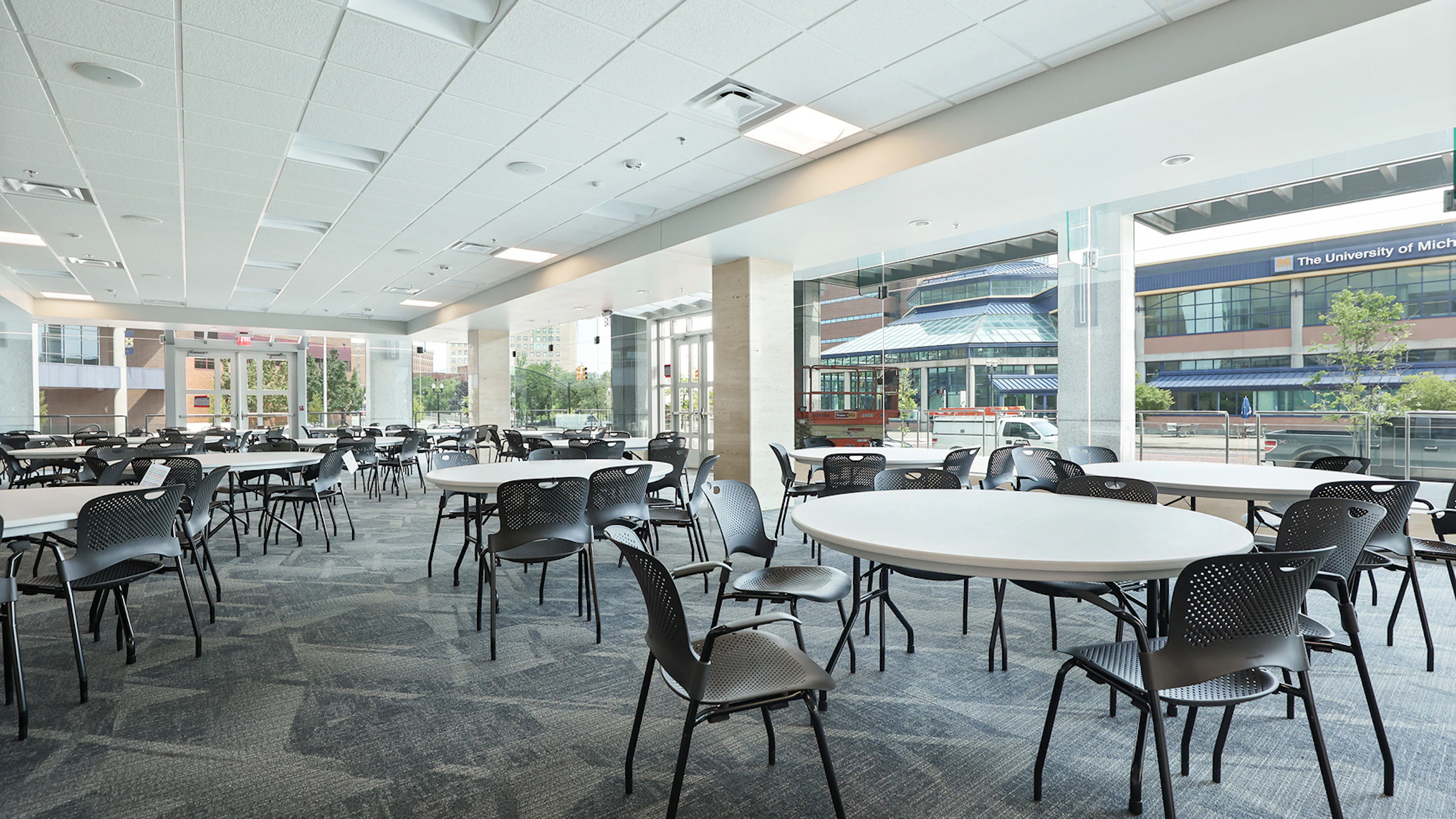 Large communal seating area furnished with white round tables with black Caper Stacking Chairs by Herman Miller.