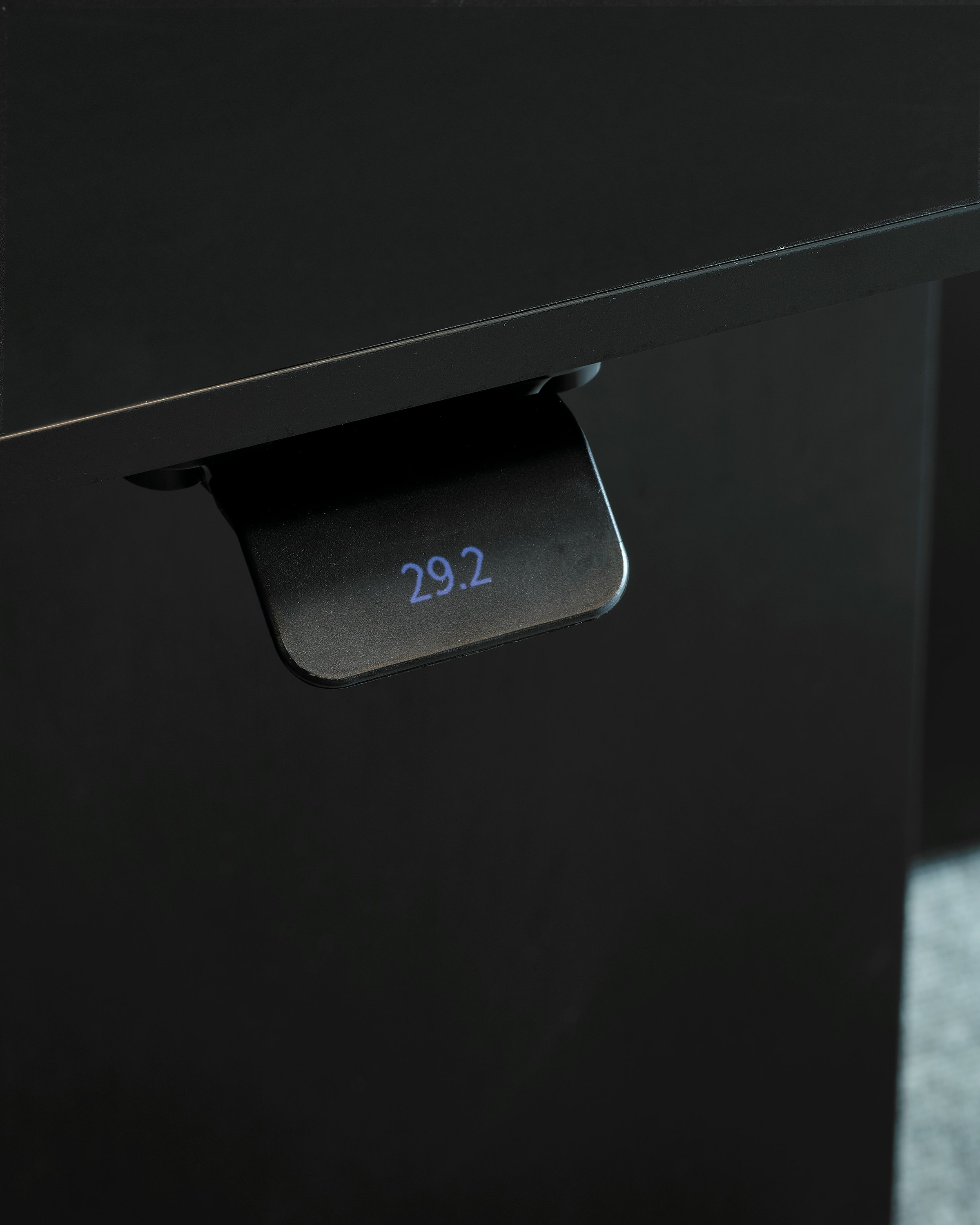 Detail view of the height-adjustable desk control for a Geiger One Private Office work surface in black with the display screen turned on showing "29.2", viewed at an angle.