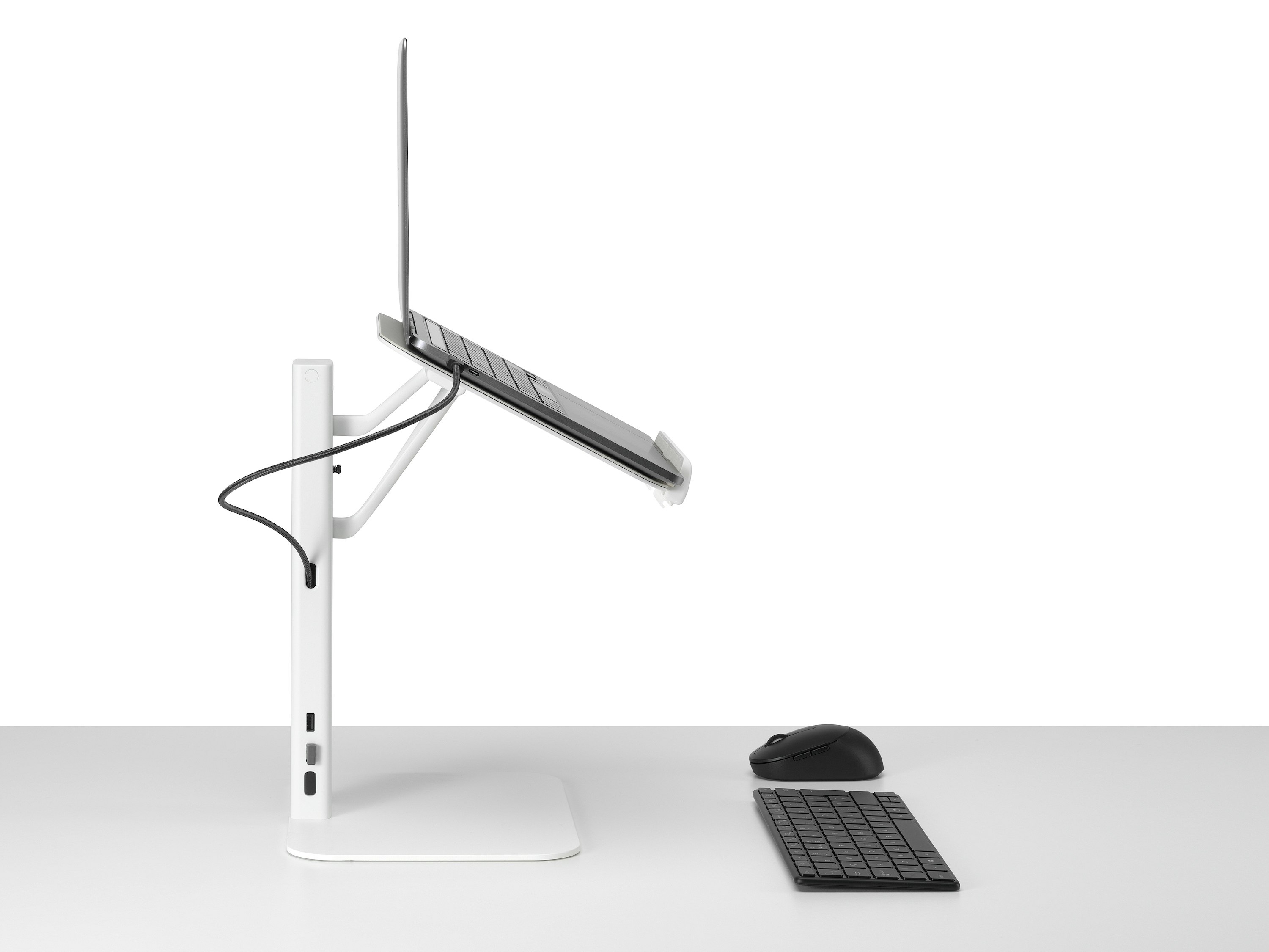 Lana laptop stand with laptop keyboard and mouse in white viewed from the side.