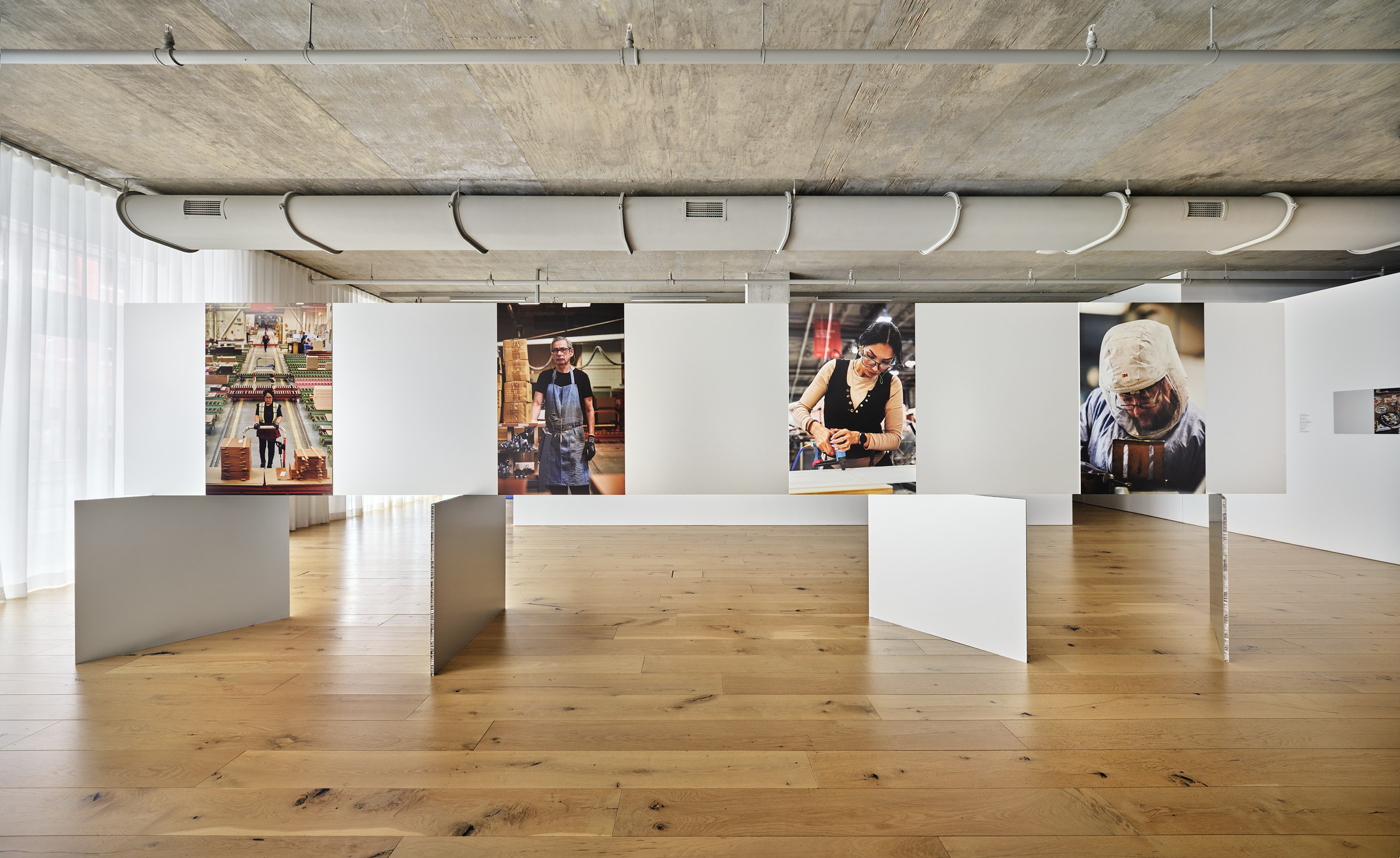 Portraits of MillerKnoll associates working in manufacturing facilities hanging in the Craft Work exhibition space at MillerKnoll Design Days.