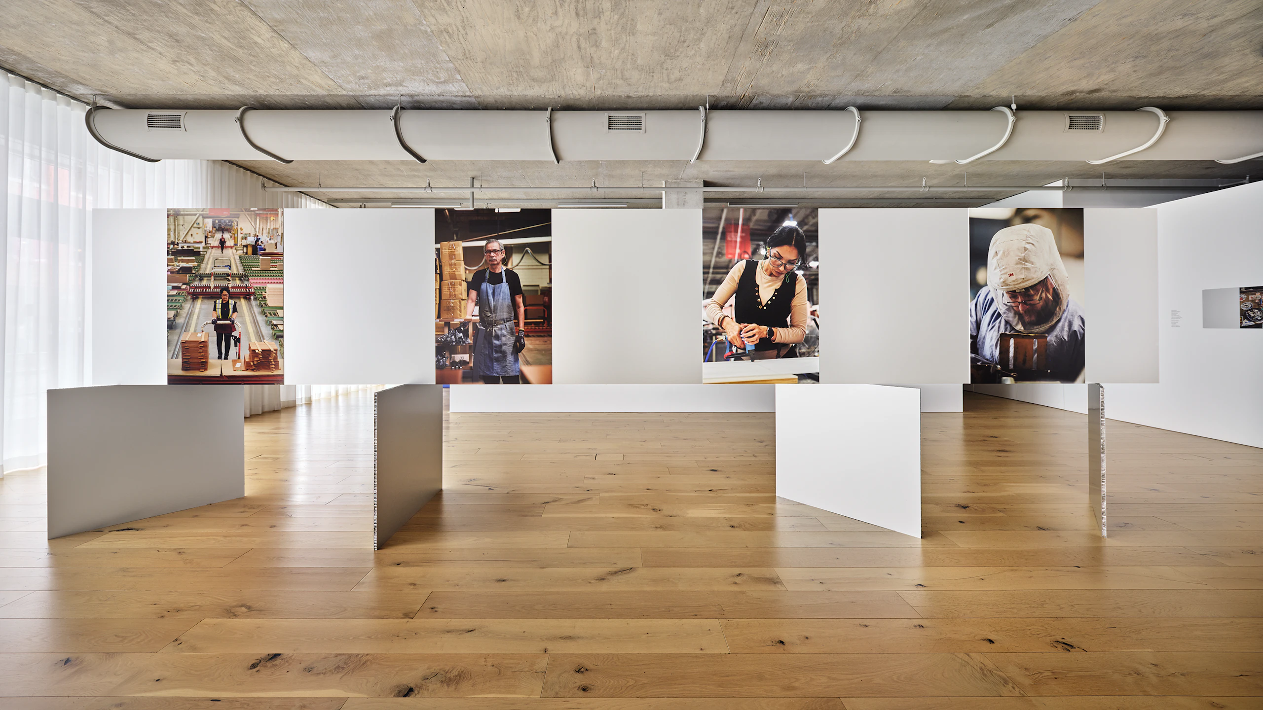 Portraits of MillerKnoll associates working in manufacturing facilities hanging in the Craft Work exhibition space at MillerKnoll Design Days.
