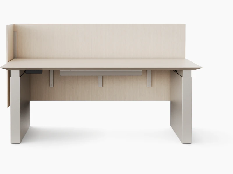 A rendering of a height adjustable table with shrouded legs and a surface attached screen on the back and one side of the table shown from straight on. The finishes of all the materials are a light color.