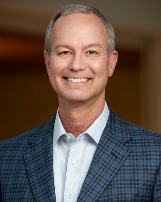 A smiling Mike R. Smith, a member of the Board of Directors of MillerKnoll, wearing a blue-checkered suit