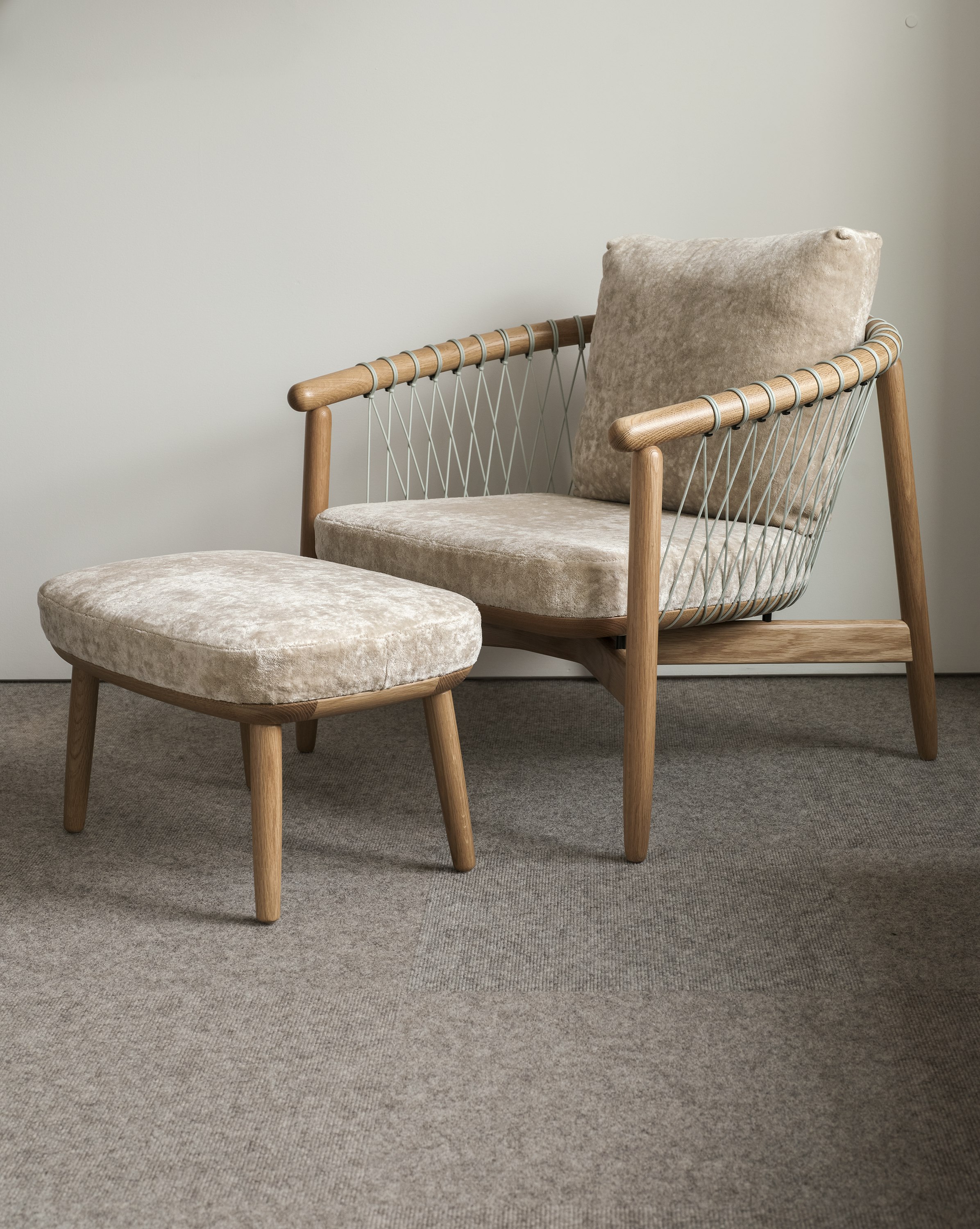 Crosshatch Chair and Ottoman with a Natural Oak frame and grey parachute cords, upholstered with Linen Velvet in Obelisk, viewed at an angle.