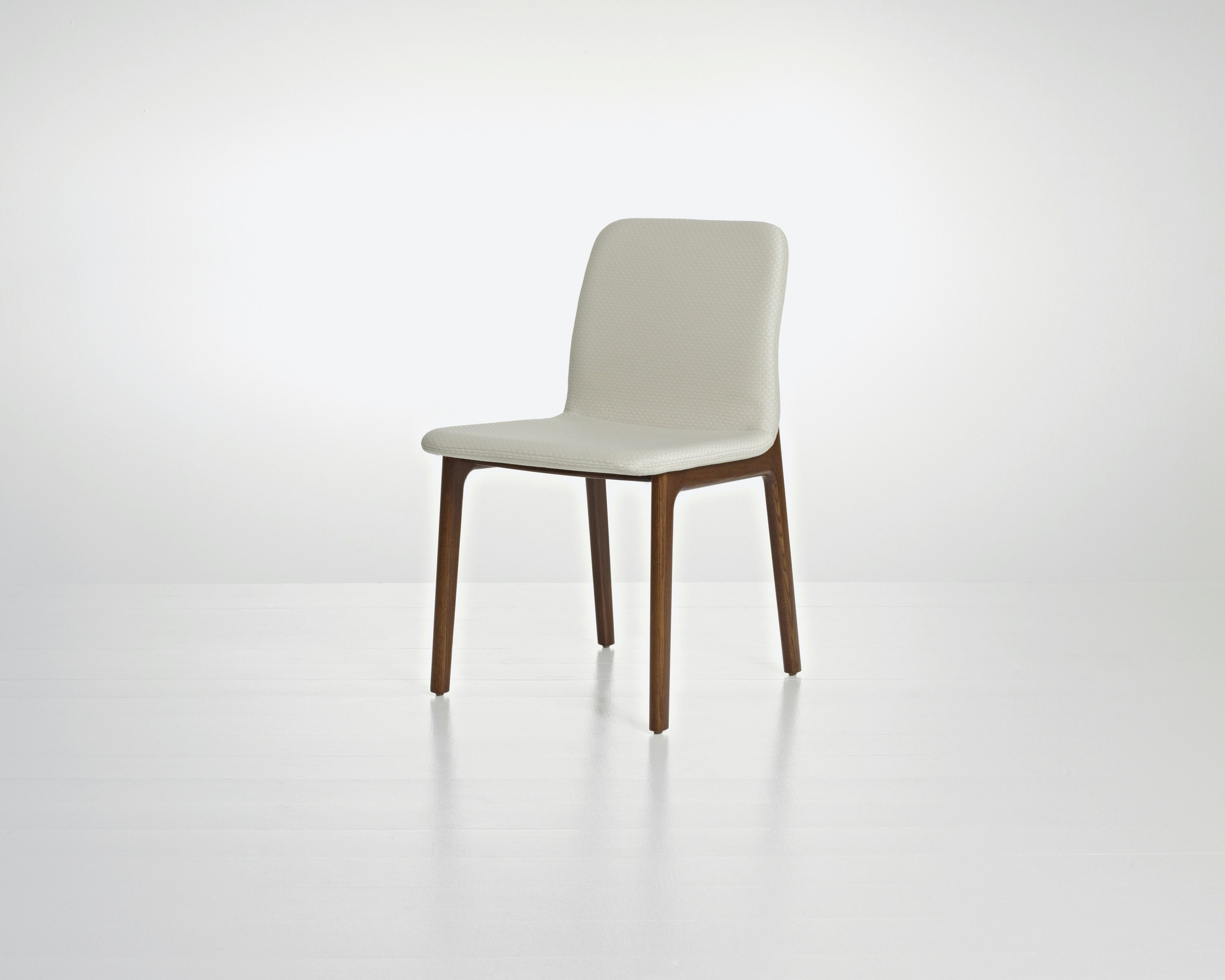 Angled view of a Deft side chair with ivory-colored fabric, a wood frame in a medium finish, and no arms.