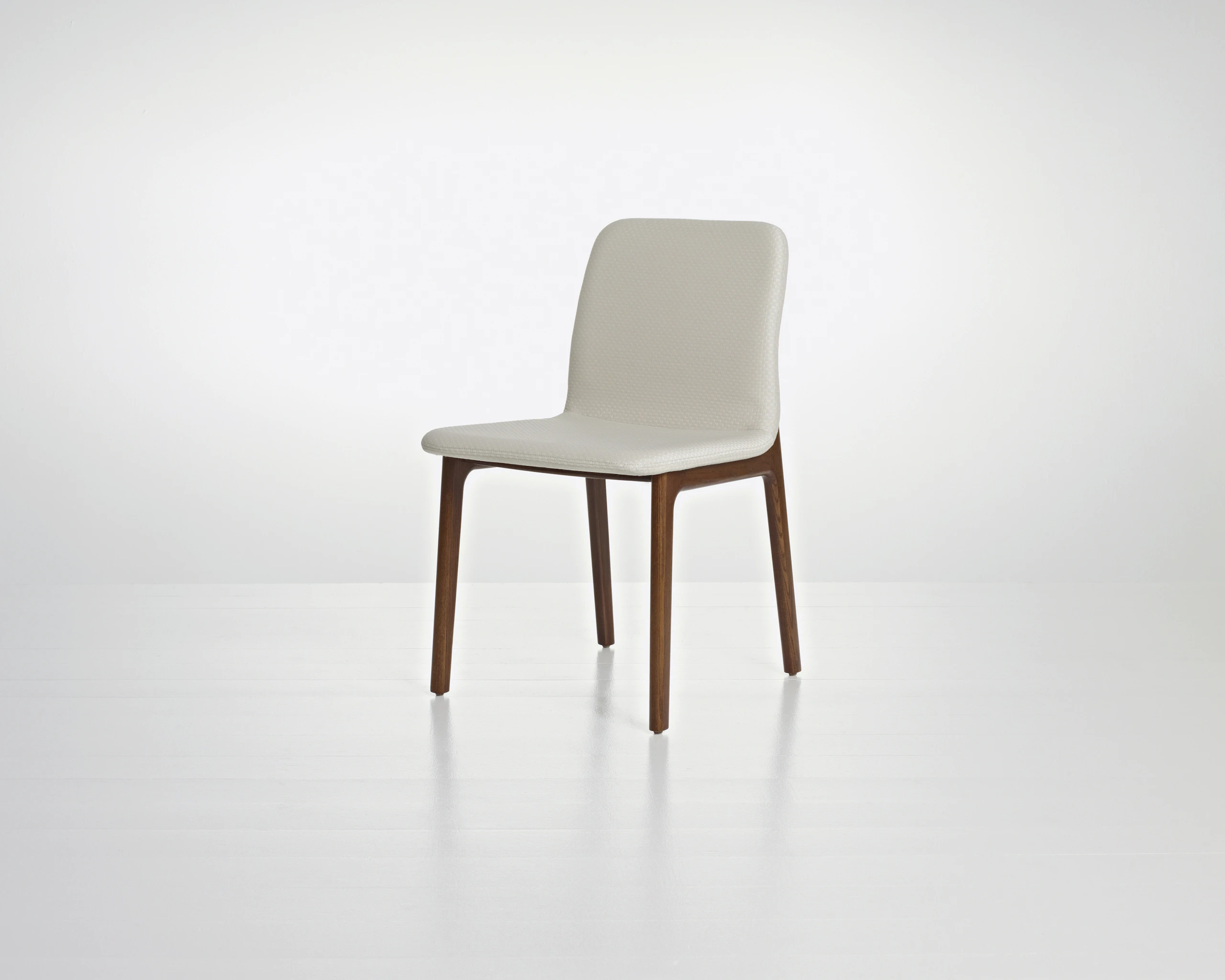 Angled view of a Deft side chair with ivory-colored fabric, a wood frame in a medium finish, and no arms.