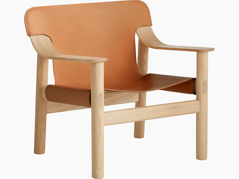 A front angle view of the Bernard Lounge Chair with oak frame and cognac leather seat and back.
