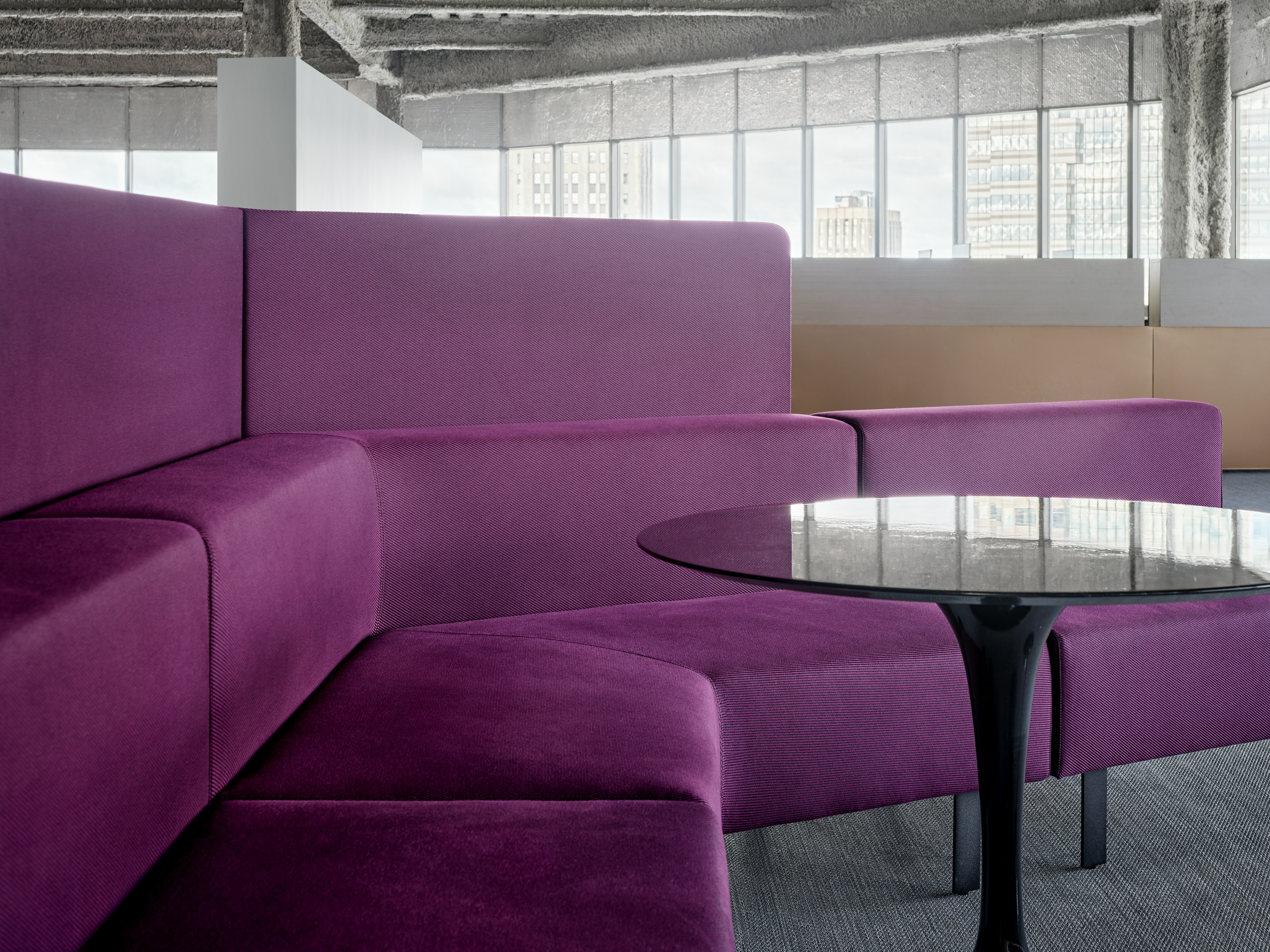 A bench style lounge seating area is set up with a small round table sitting in front of the bench seating. There are also privacy screens attached to the back of the lounge seating.